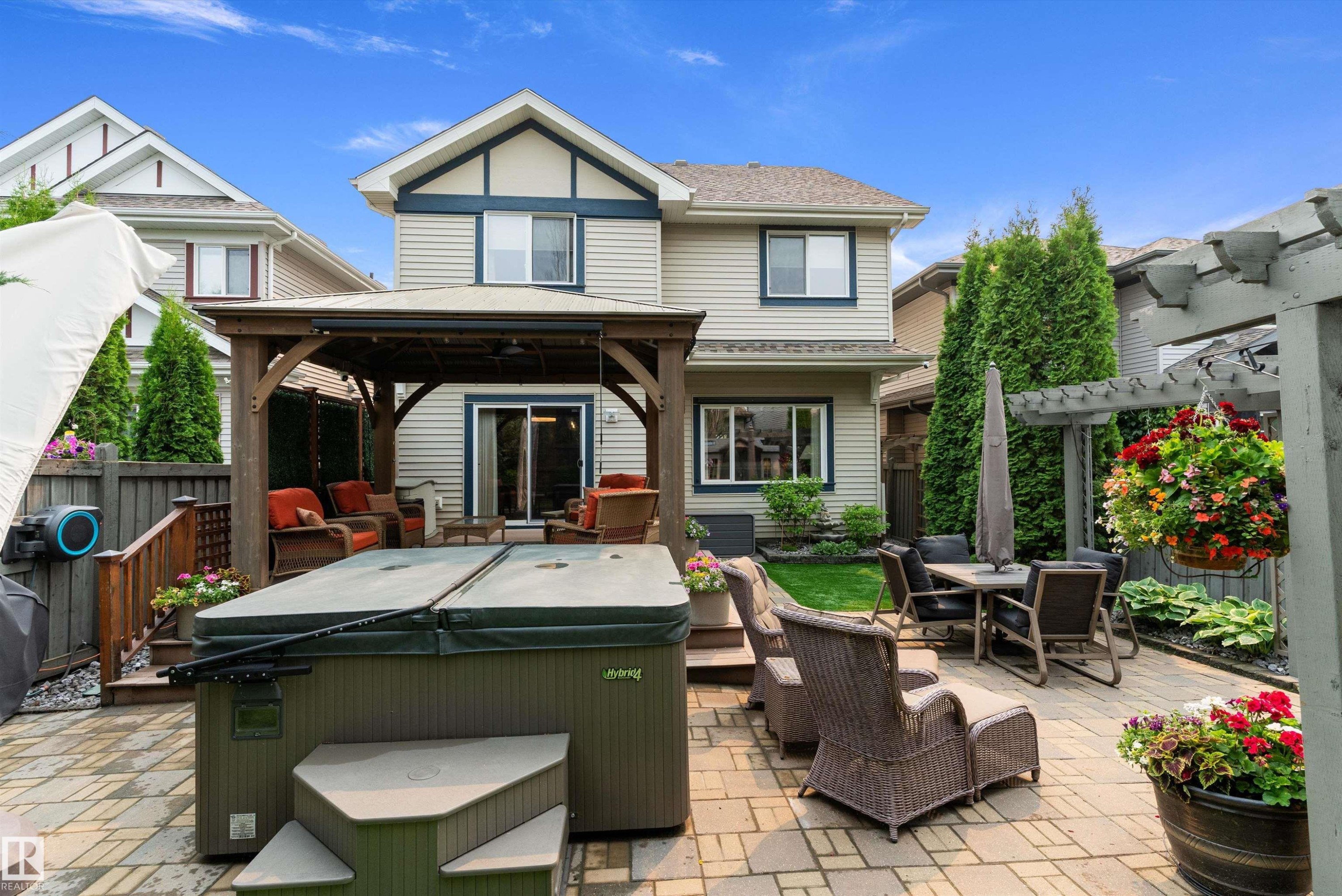 Expansive paver patio featuring a built-in hot tub, a covered gazebo, and a secondary dining area - 1097 Armitage Crescent, Edmonton, AB