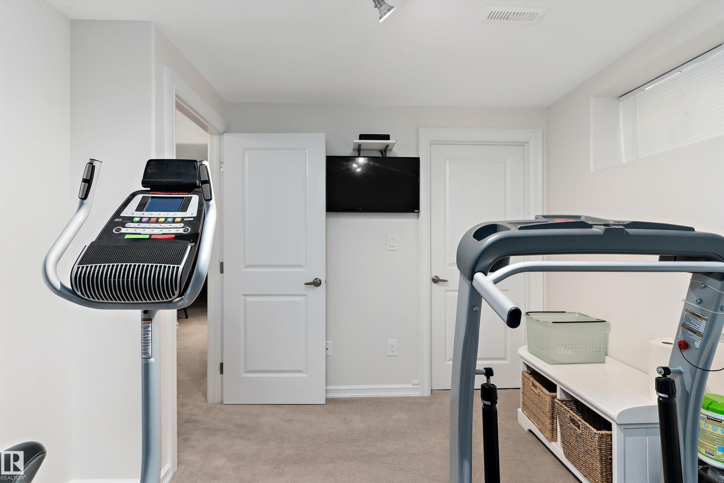 Carpeted room featuring recessed lighting, a wall-mounted television, and two paneled doors - 1097 Armitage Crescent, Edmonton, AB