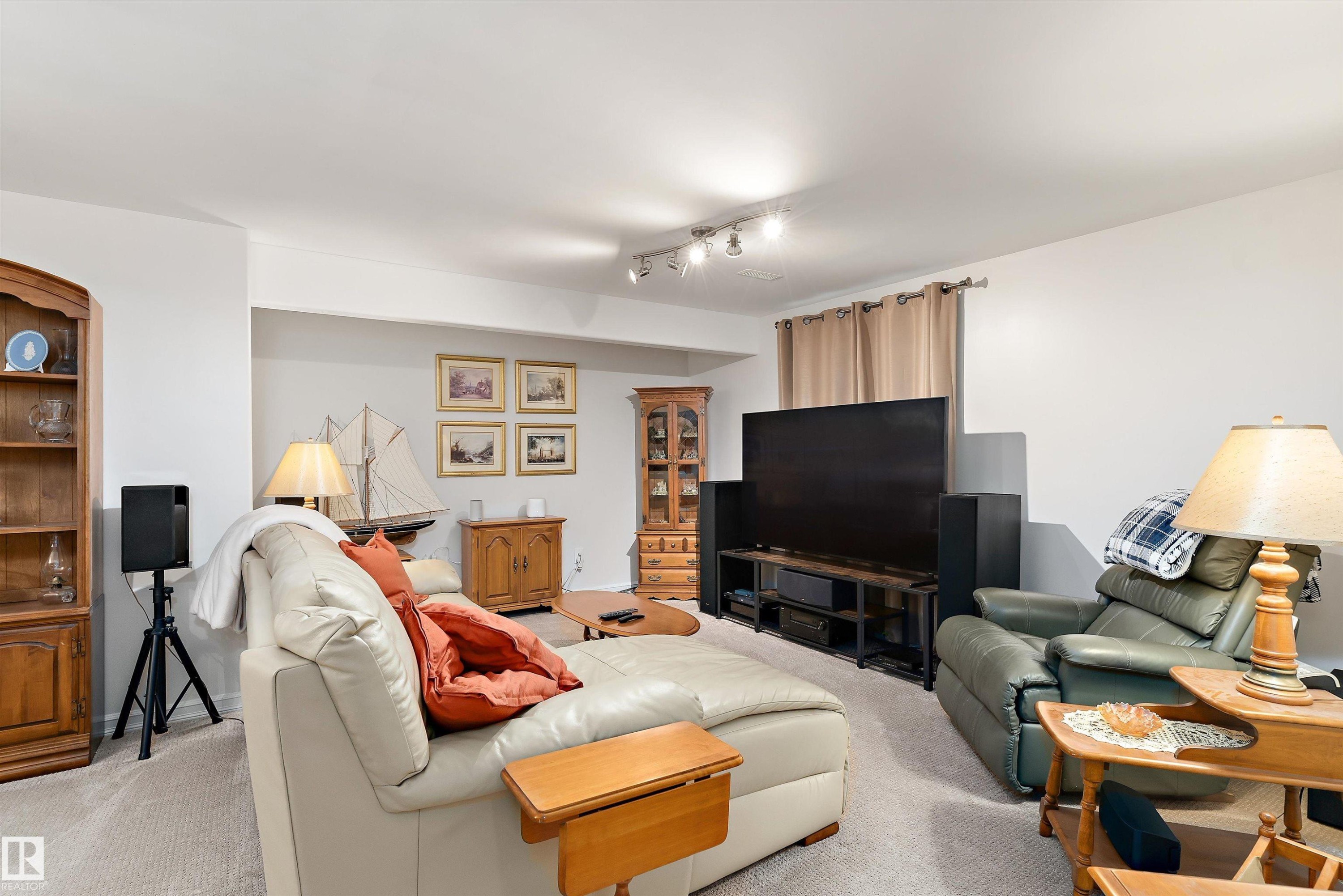 Carpeted living area featuring track lighting, light-toned walls, and a recessed ceiling section - 1097 Armitage Crescent, Edmonton, AB