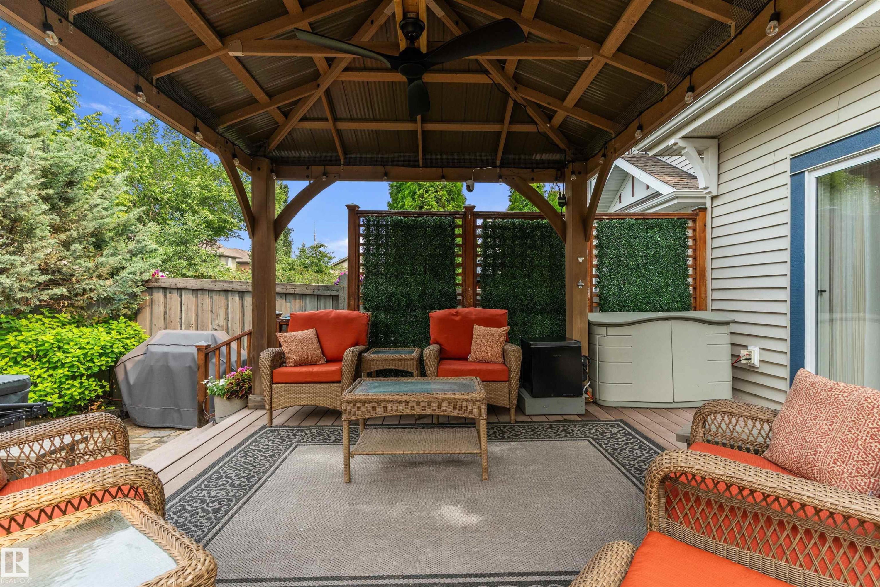 Spacious covered patio area featuring a slatted wood ceiling, built-in lighting, and a ceiling fan - 1097 Armitage Crescent, Edmonton, AB