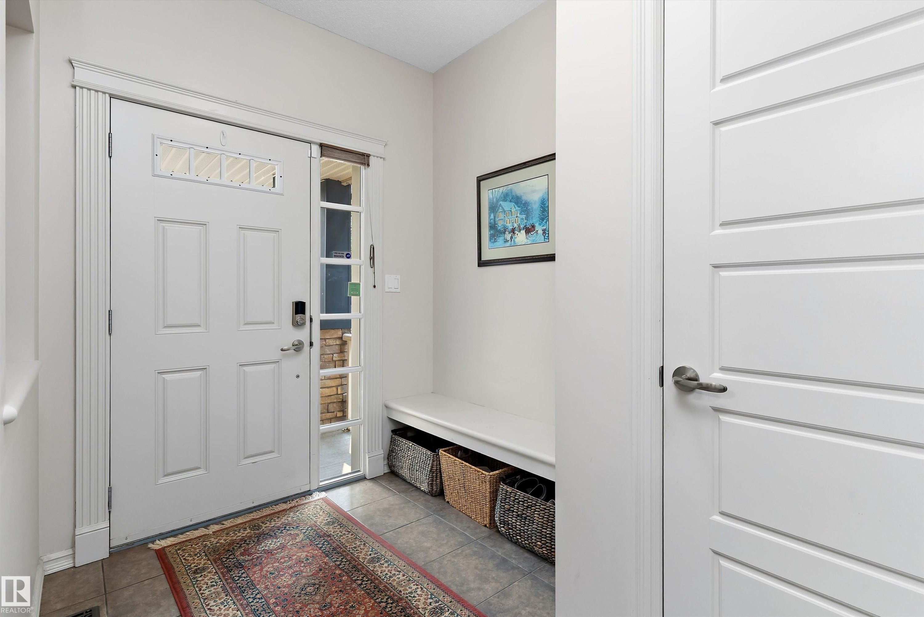 Entryway featuring a white panel door with transom window and sidelight, tile flooring, and a built-in bench - 1097 Armitage Crescent, Edmonton, AB