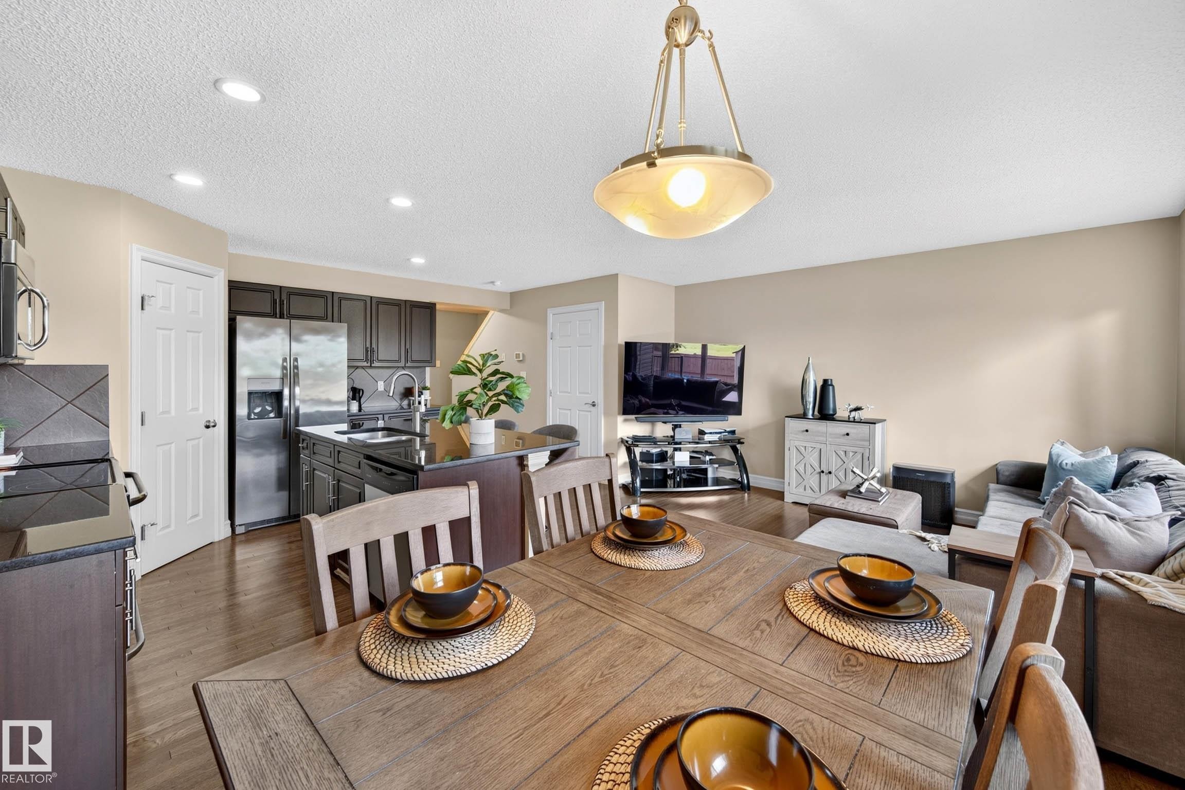 Open-concept living space with wood-finish flooring, recessed lighting, and a neutral wall color - 12119 167A Avenue, Edmonton, AB