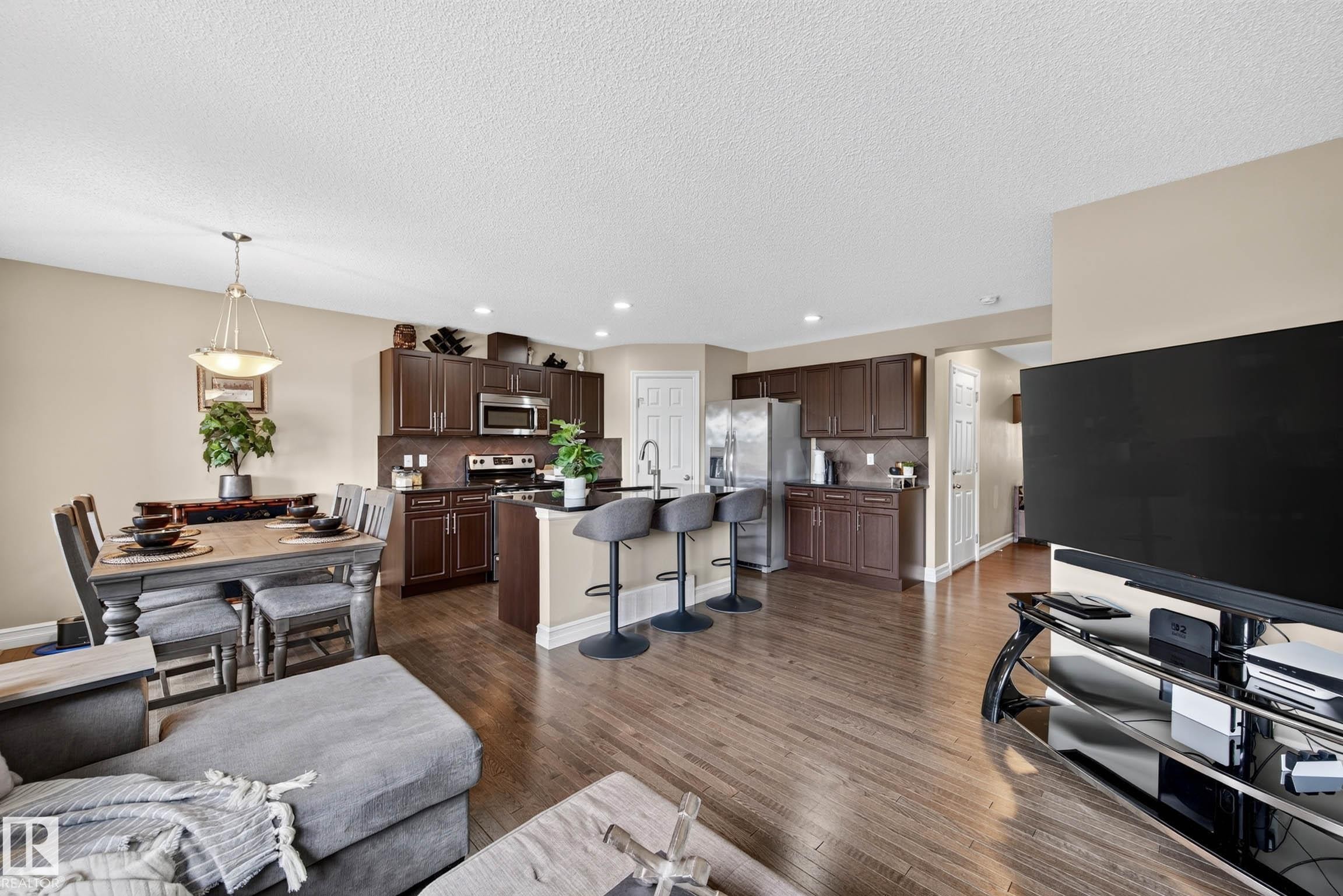 Open-concept living area featuring wood-finish flooring, recessed lighting, and a neutral color palette - 12119 167A Avenue, Edmonton, AB