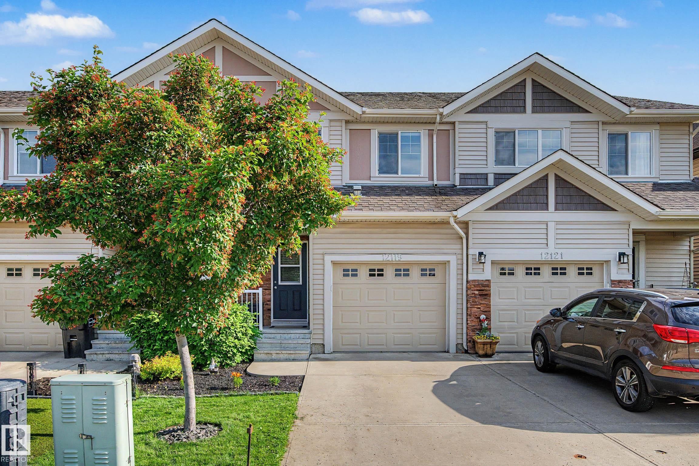 Two-story townhome with light-colored siding and a dark brown front door - 12119 167A Avenue, Edmonton, AB