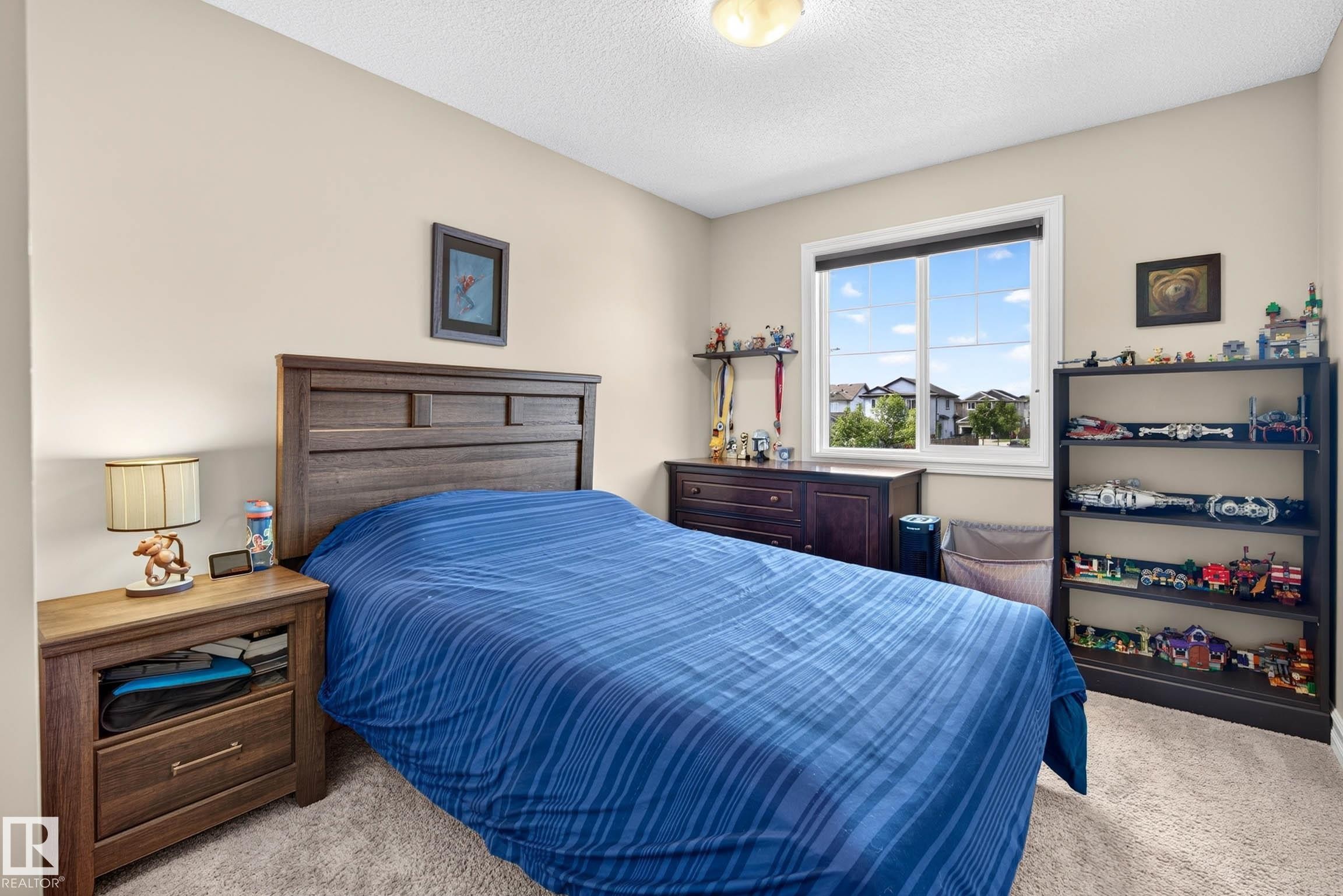 Bedroom featuring a window with white trim, wood-finish headboard, and neutral carpeting - 12119 167A Avenue, Edmonton, AB