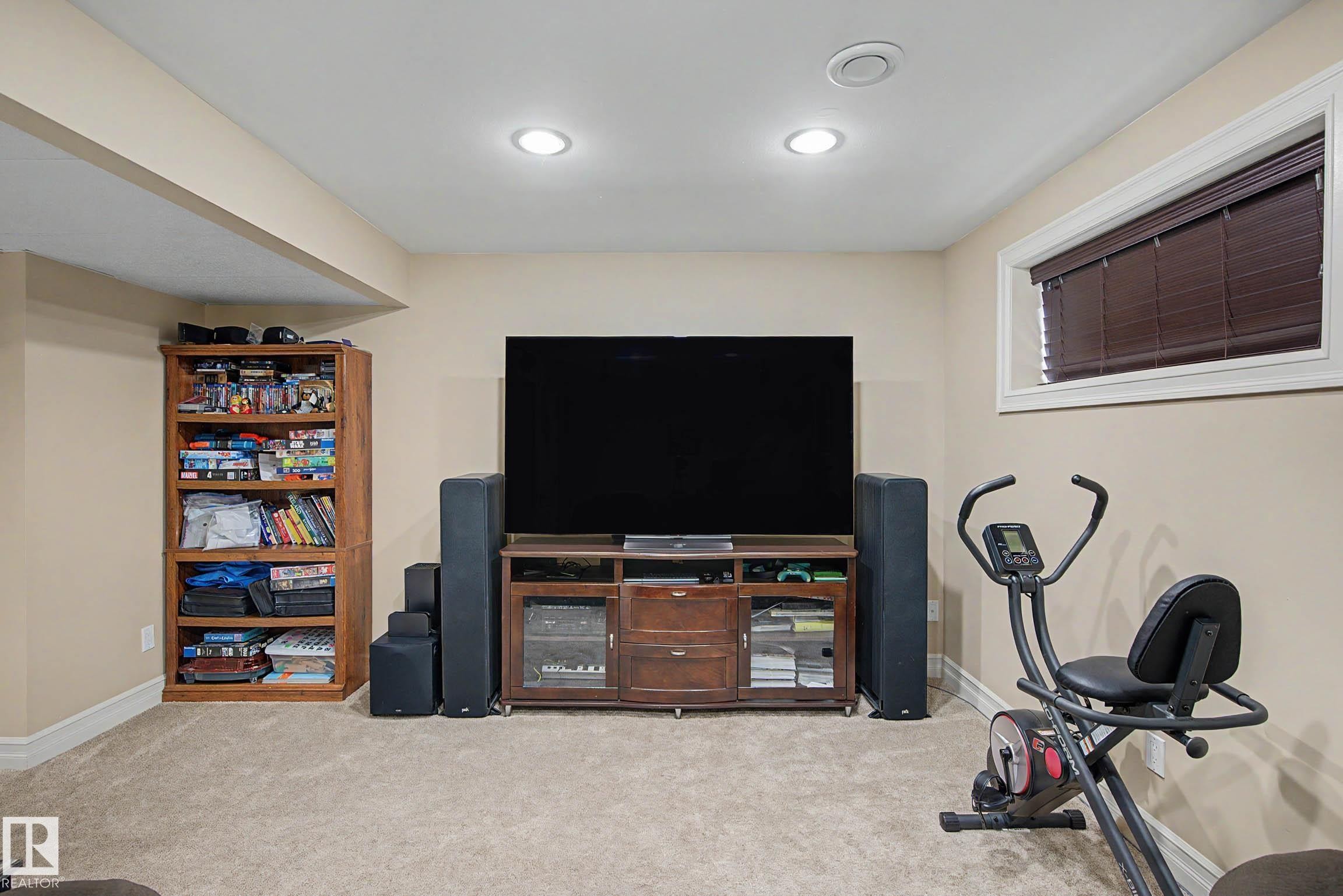 Spacious room featuring neutral carpeting, recessed lighting, and a window with blinds - 12119 167A Avenue, Edmonton, AB
