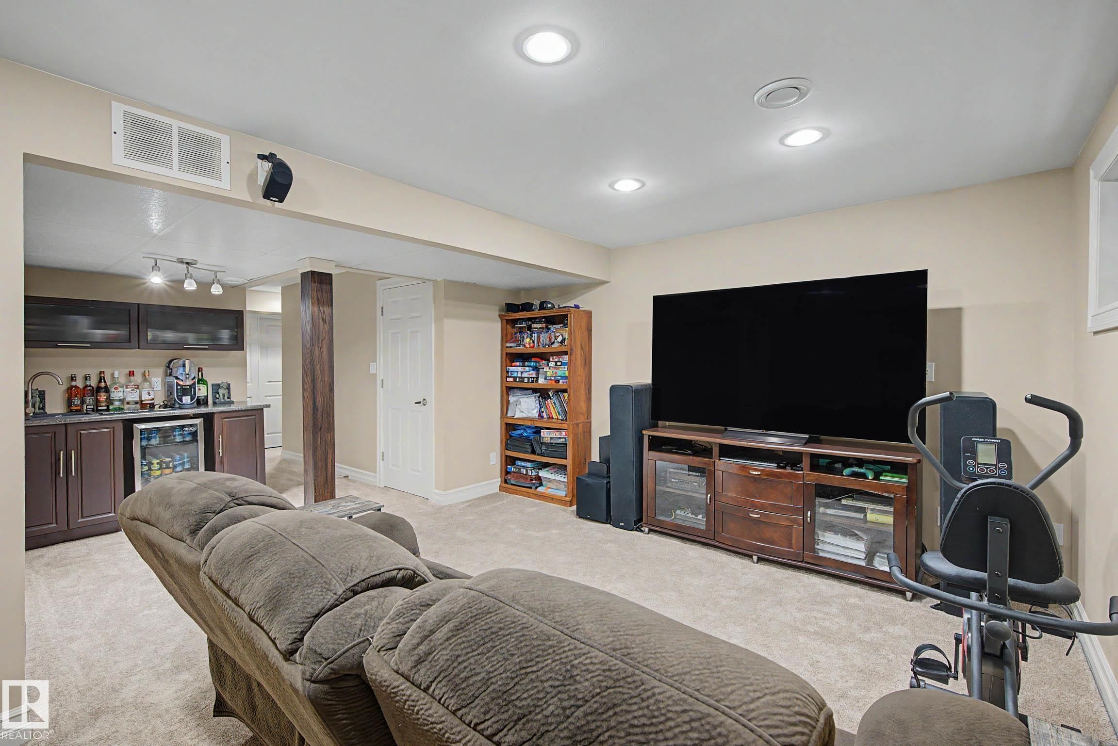 Finished lower level featuring recessed lighting, a built-in wet bar with dark cabinetry and a beverage refrigerator, and a dedicated entertainment area - 12119 167A Avenue, Edmonton, AB