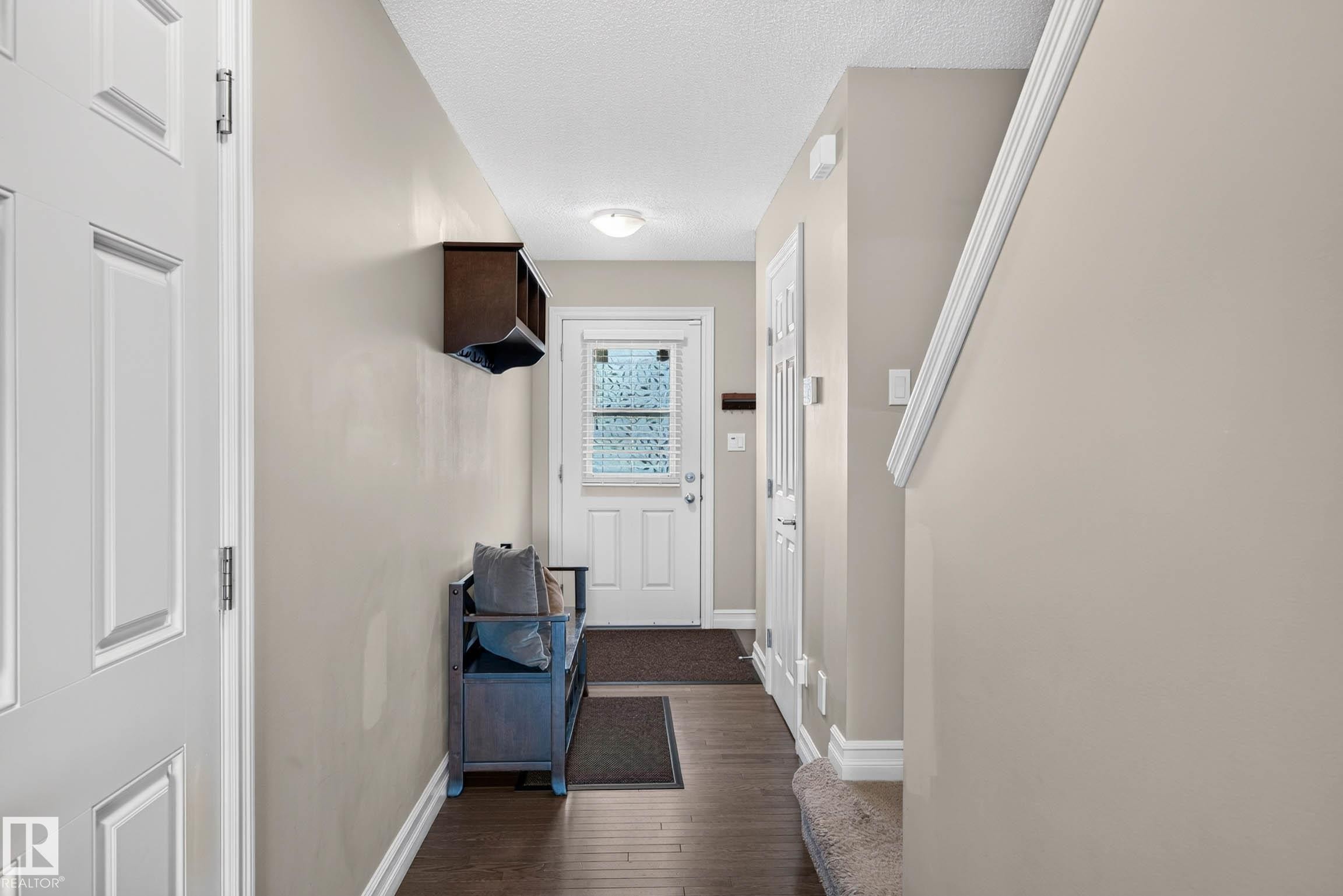Entryway featuring dark wood-finish flooring, light neutral wall paint, and white trim molding - 12119 167A Avenue, Edmonton, AB
