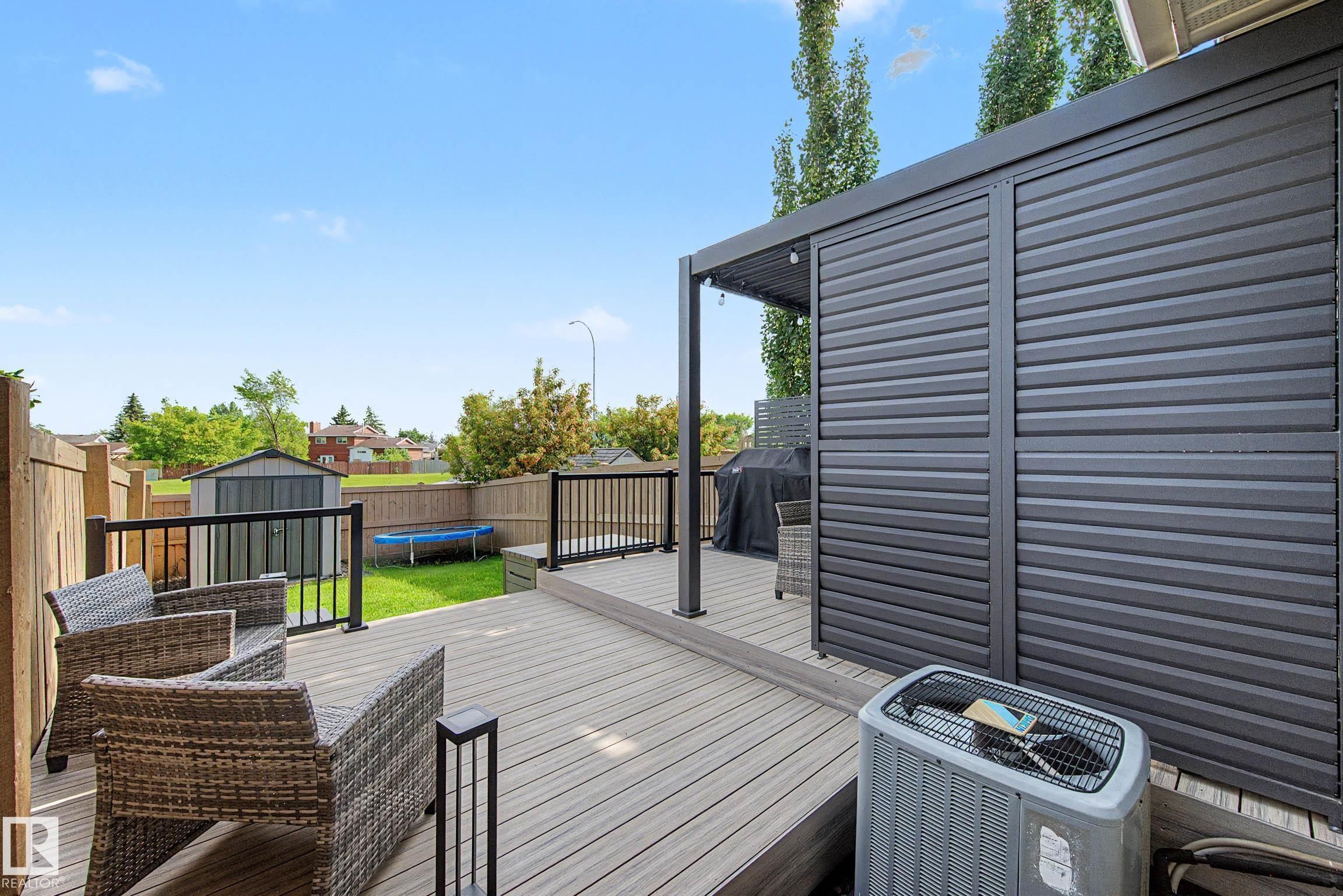 Expansive backyard deck featuring composite wood-finish decking, black metal railings, and a privacy screen with a slatted design - 12119 167A Avenue, Edmonton, AB