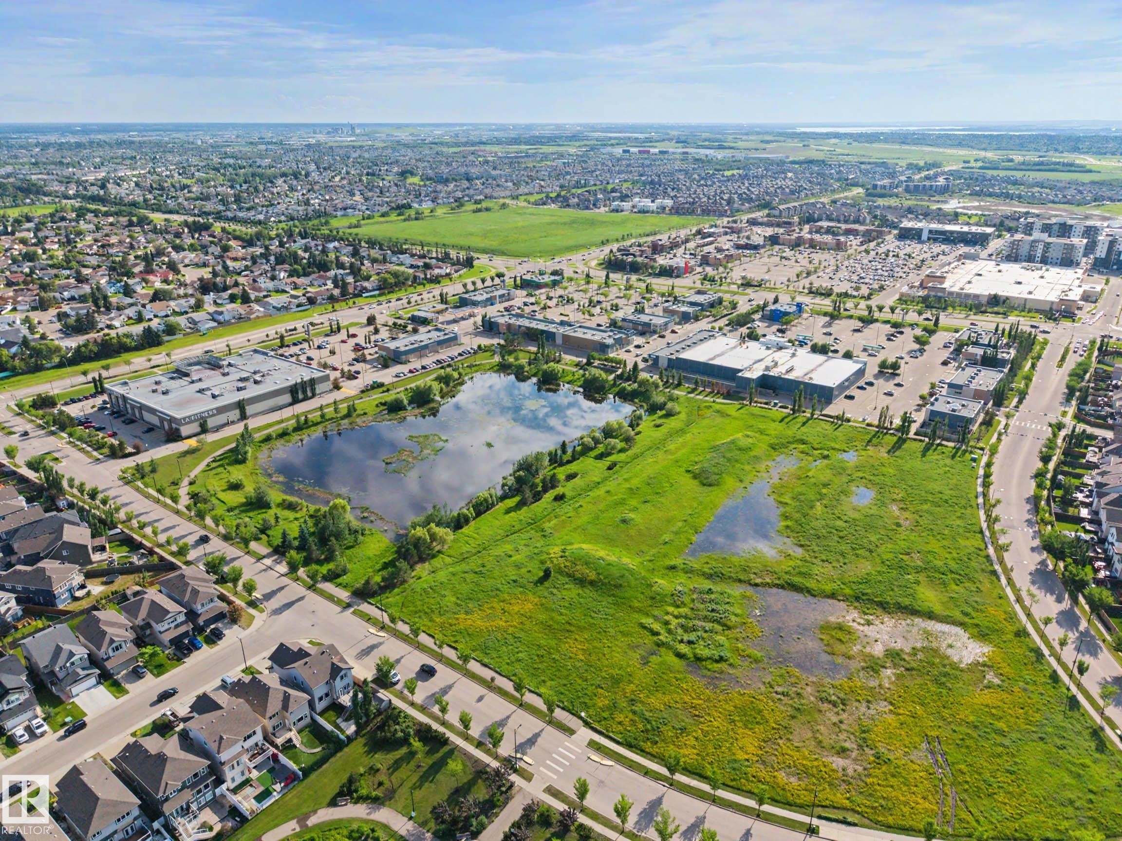 Aerial perspective showcasing a developed neighborhood with diverse architectural styles, commercial buildings, and extensive green spaces - 12119 167A Avenue, Edmonton, AB