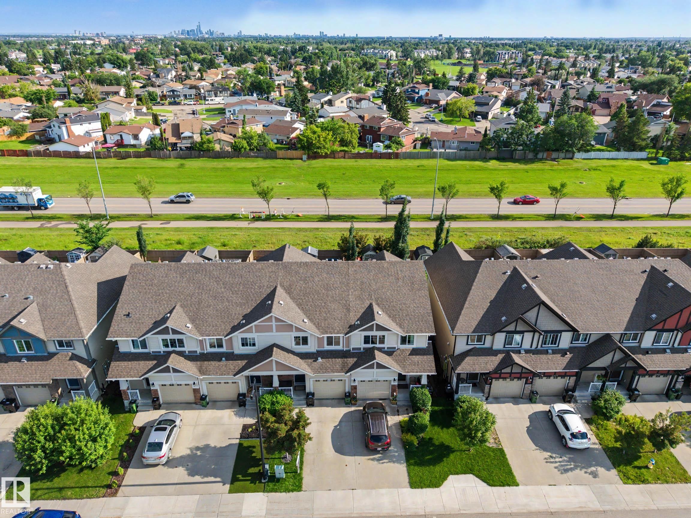 Aerial perspective showcasing a row of townhomes with attached garages and paved driveways - 12119 167A Avenue, Edmonton, AB