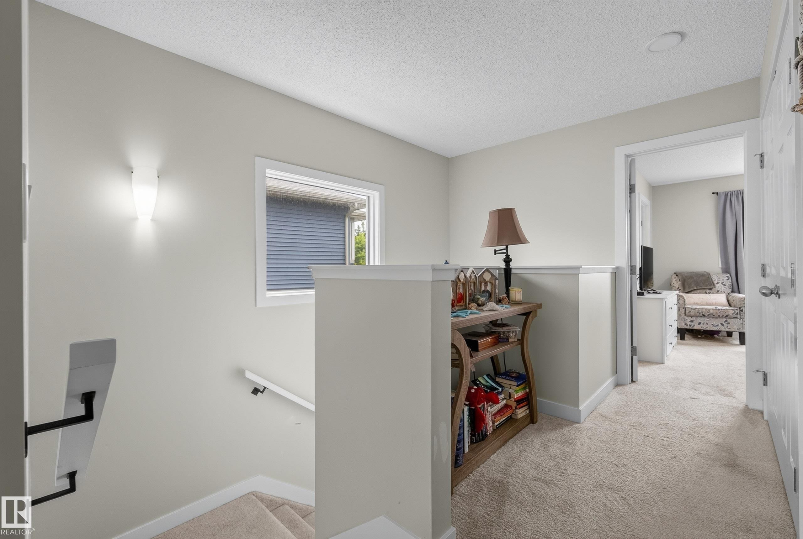 Upper-level hallway featuring neutral carpeting, a white balustrade, and a recessed wall light - 5129 Lark Crescent Nw, Edmonton, AB - Indoor Photo Showing Other Room