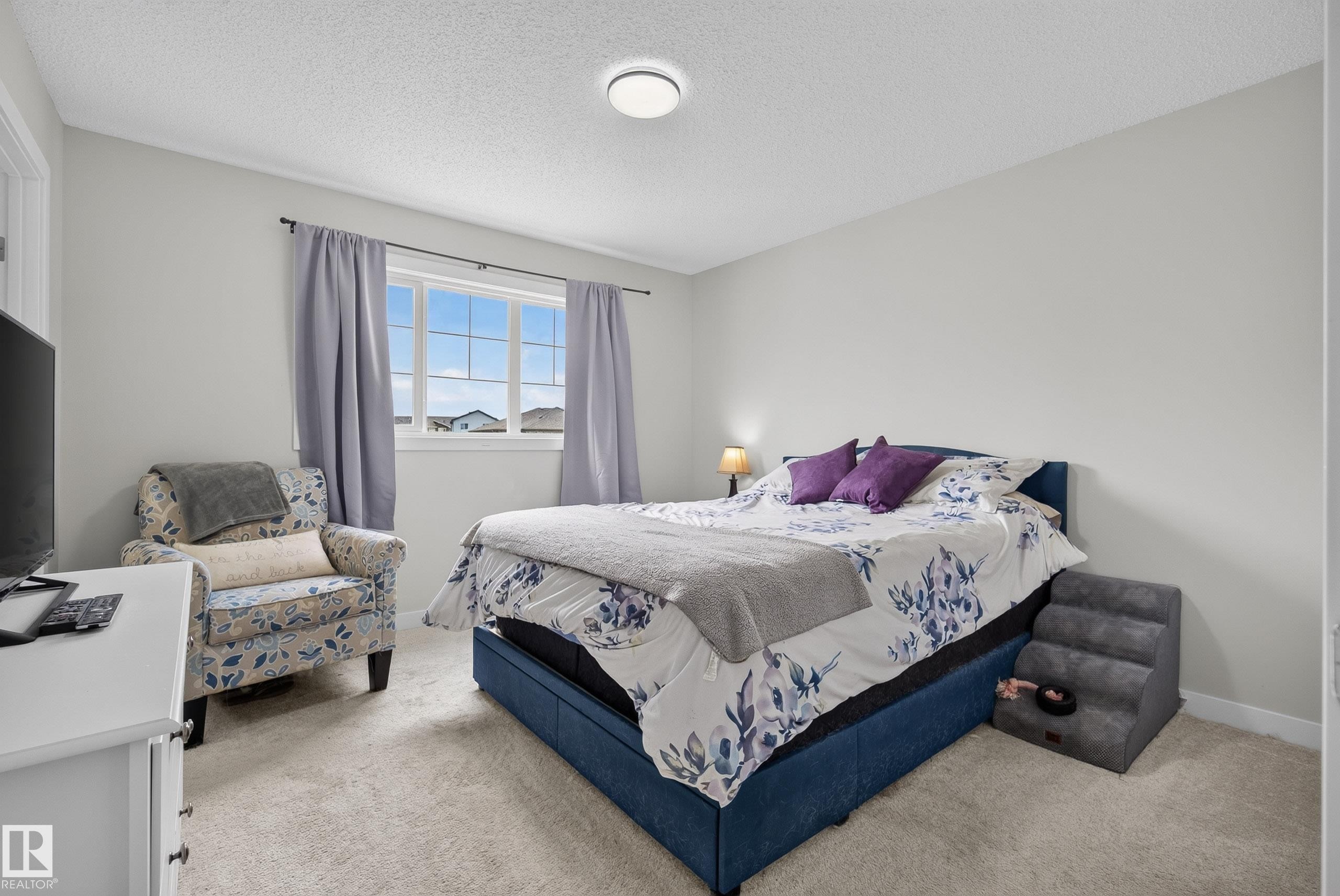 Neutral-toned bedroom featuring a light-colored carpet, a multi-paned window, and a flush-mount ceiling light - 5129 Lark Crescent Nw, Edmonton, AB - Indoor Photo Showing Bedroom