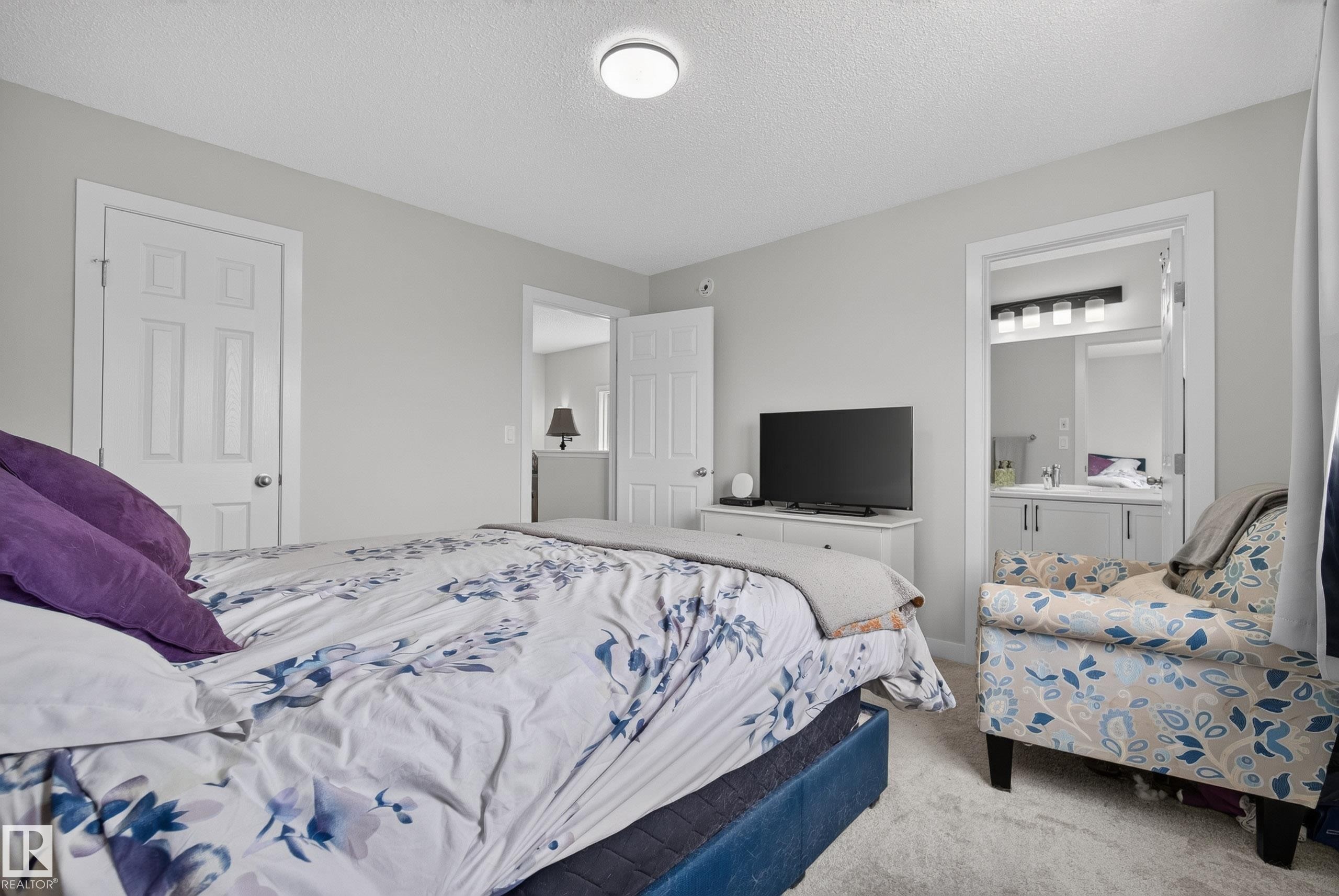 Carpeted bedroom with light gray walls, a flush-mount ceiling light, and white paneled doors - 5129 Lark Crescent Nw, Edmonton, AB - Indoor Photo Showing Bedroom
