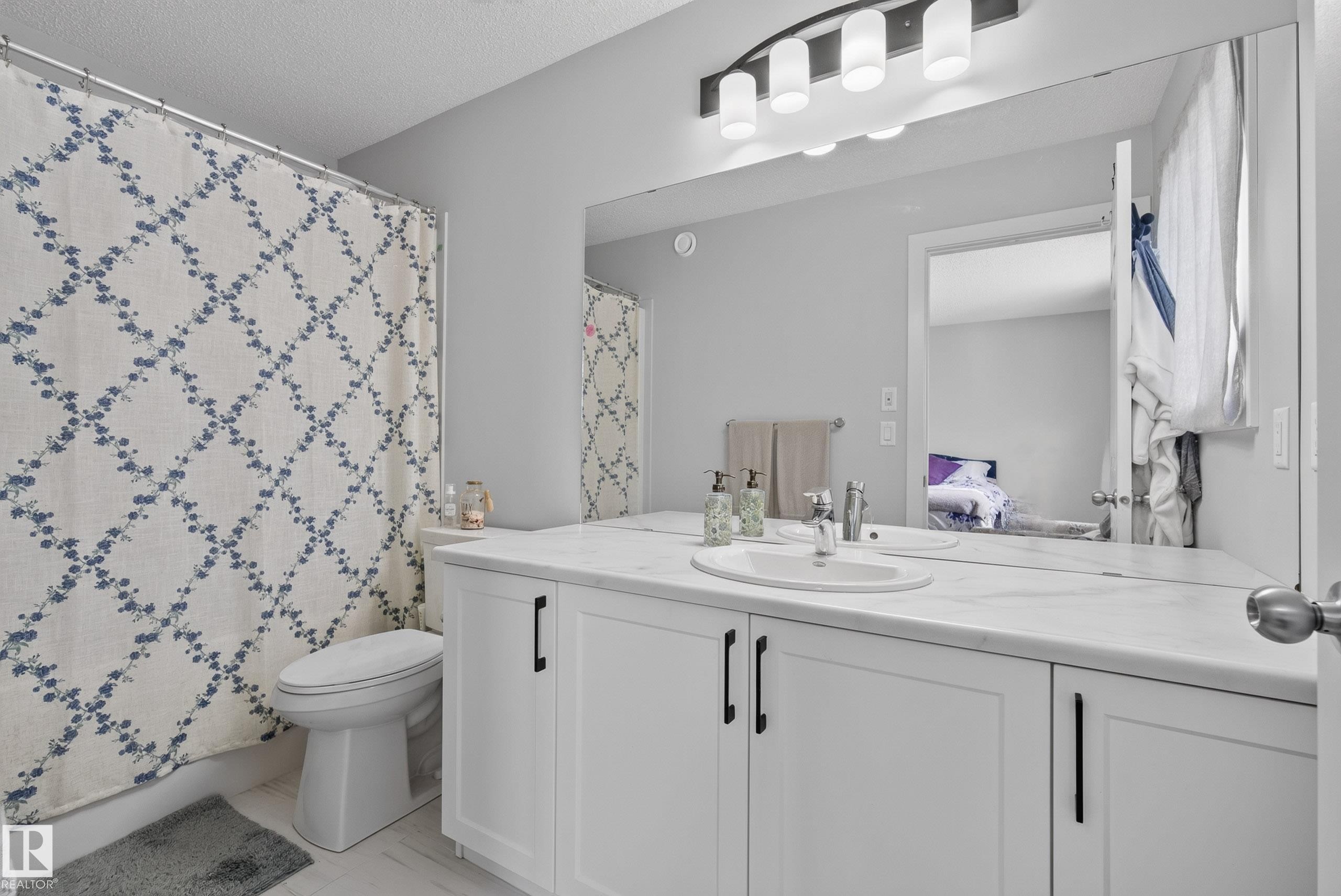 Bathroom featuring a white vanity with panel cabinetry, a single undermount sink, and a spacious countertop - 5129 Lark Crescent Nw, Edmonton, AB - Indoor Photo Showing Bathroom