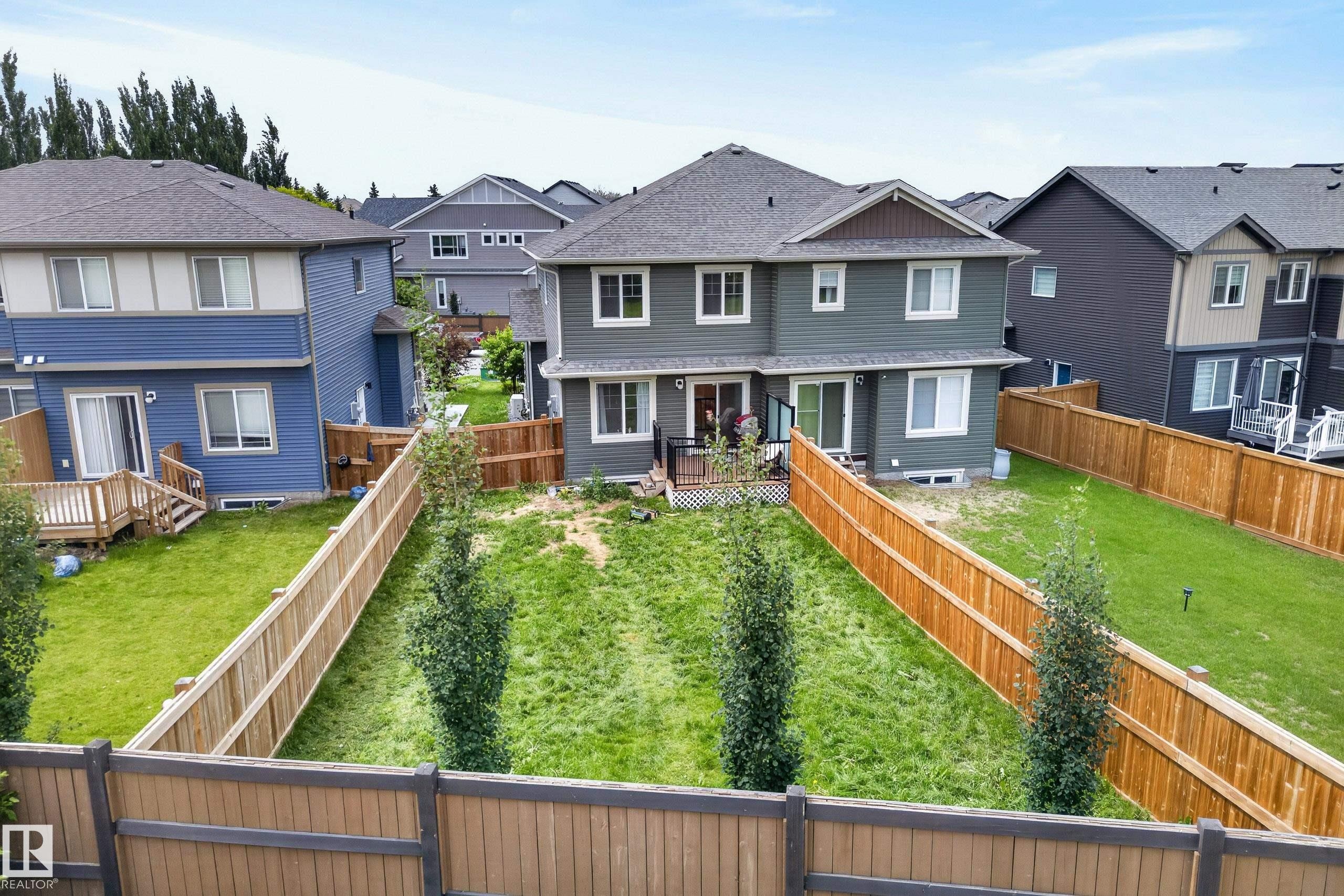 Rear exterior featuring a spacious fenced yard, a rear deck, and a second-story balcony - 5129 Lark Crescent Nw, Edmonton, AB - Outdoor With Deck Patio Veranda