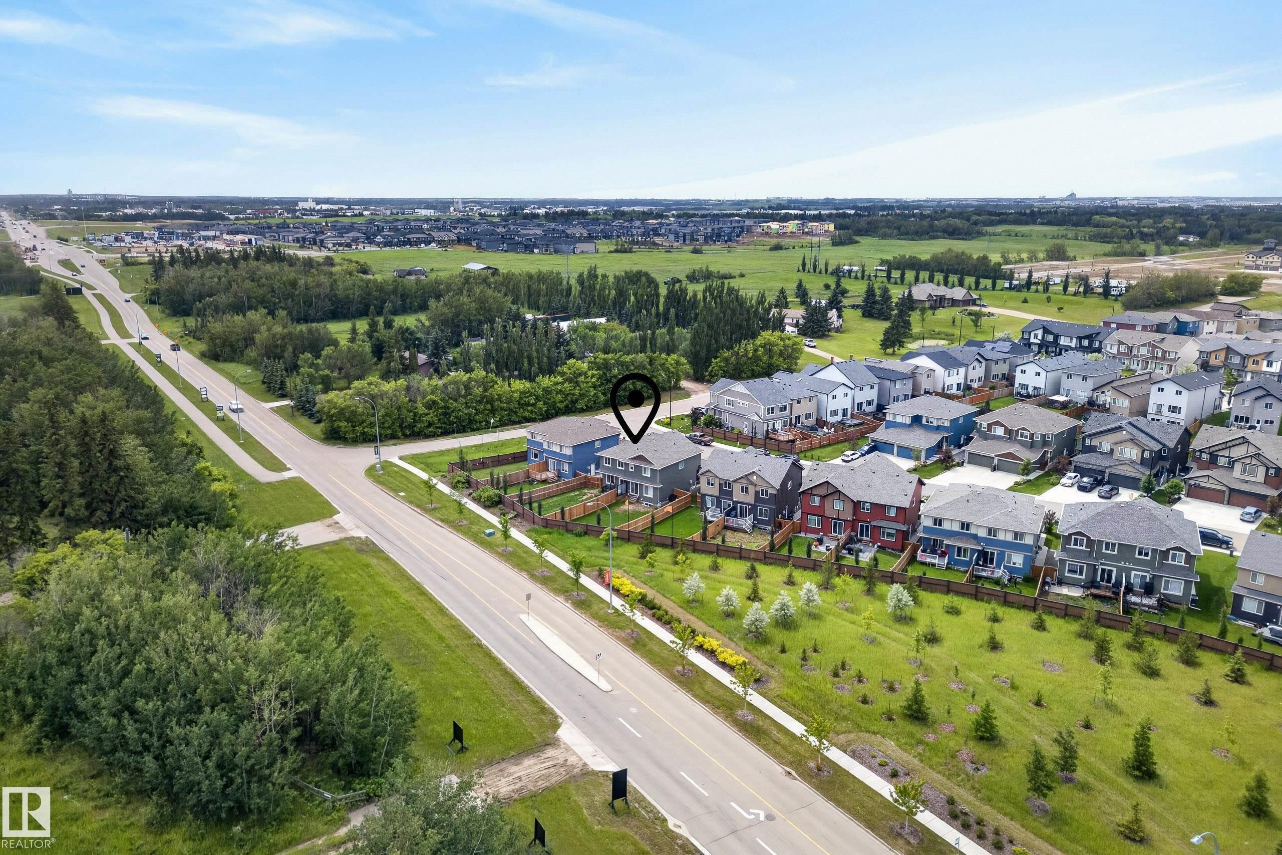 Aerial perspective showcasing a residential development bordering open green spaces and a multi-lane roadway - 5129 Lark Crescent Nw, Edmonton, AB - Outdoor With View