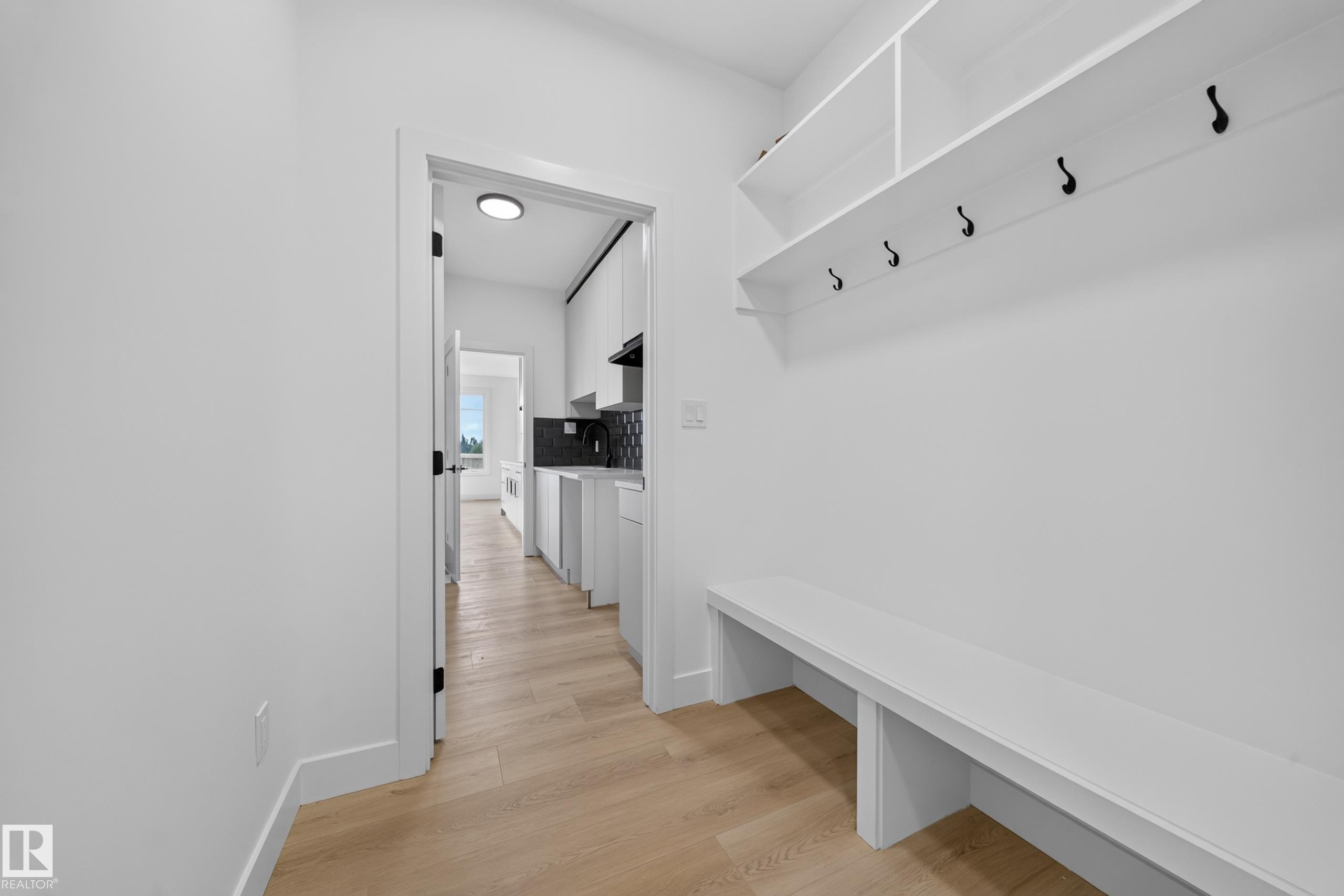 Contemporary kitchen featuring light gray and black cabinetry with gold-tone hardware, white countertops, and a gray subway tile backsplash - 803 30 Avenue, Edmonton, AB