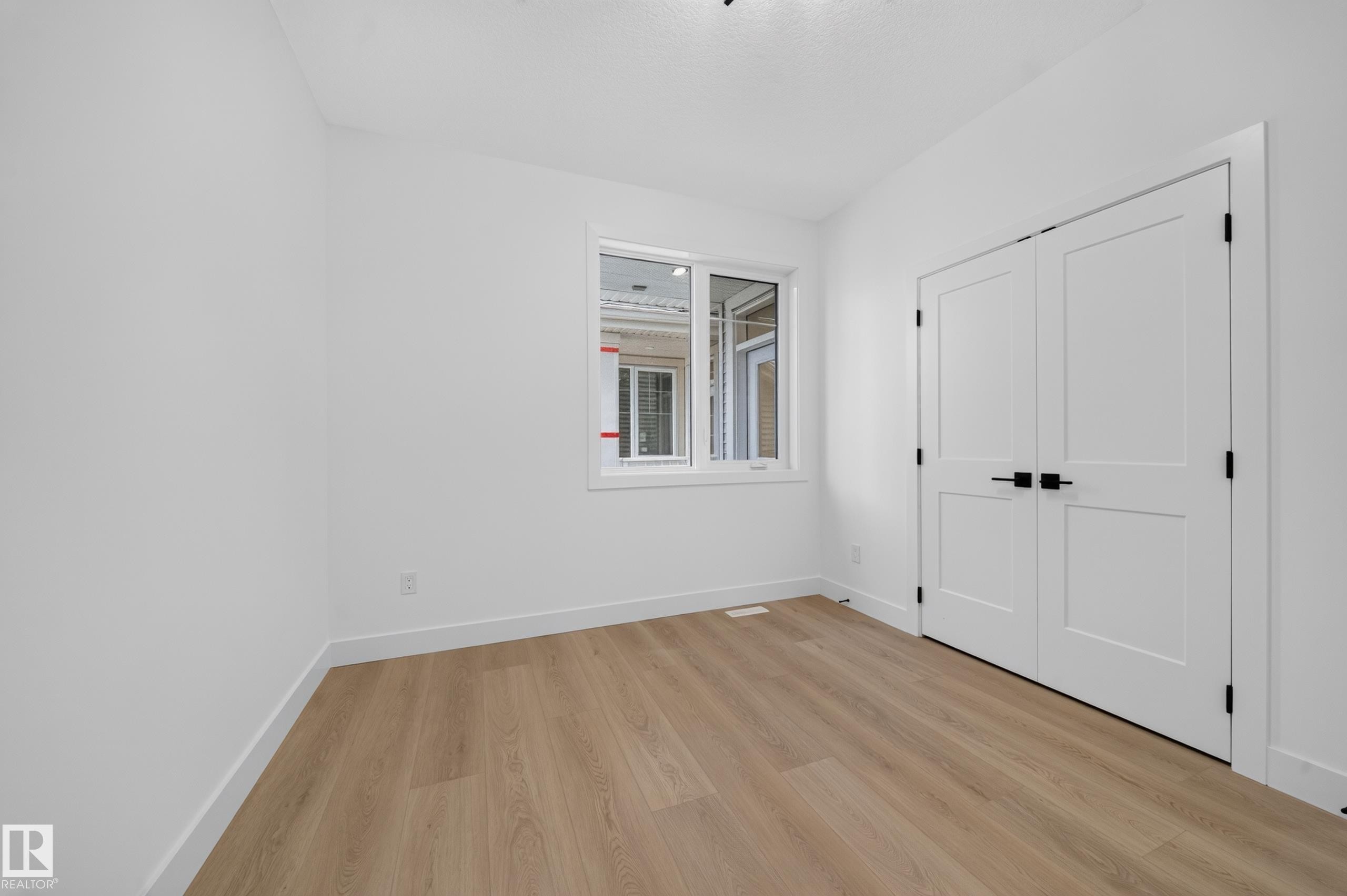 Bright room featuring light wood-finish flooring, white walls, and a contemporary ceiling light fixture - 803 30 Avenue, Edmonton, AB