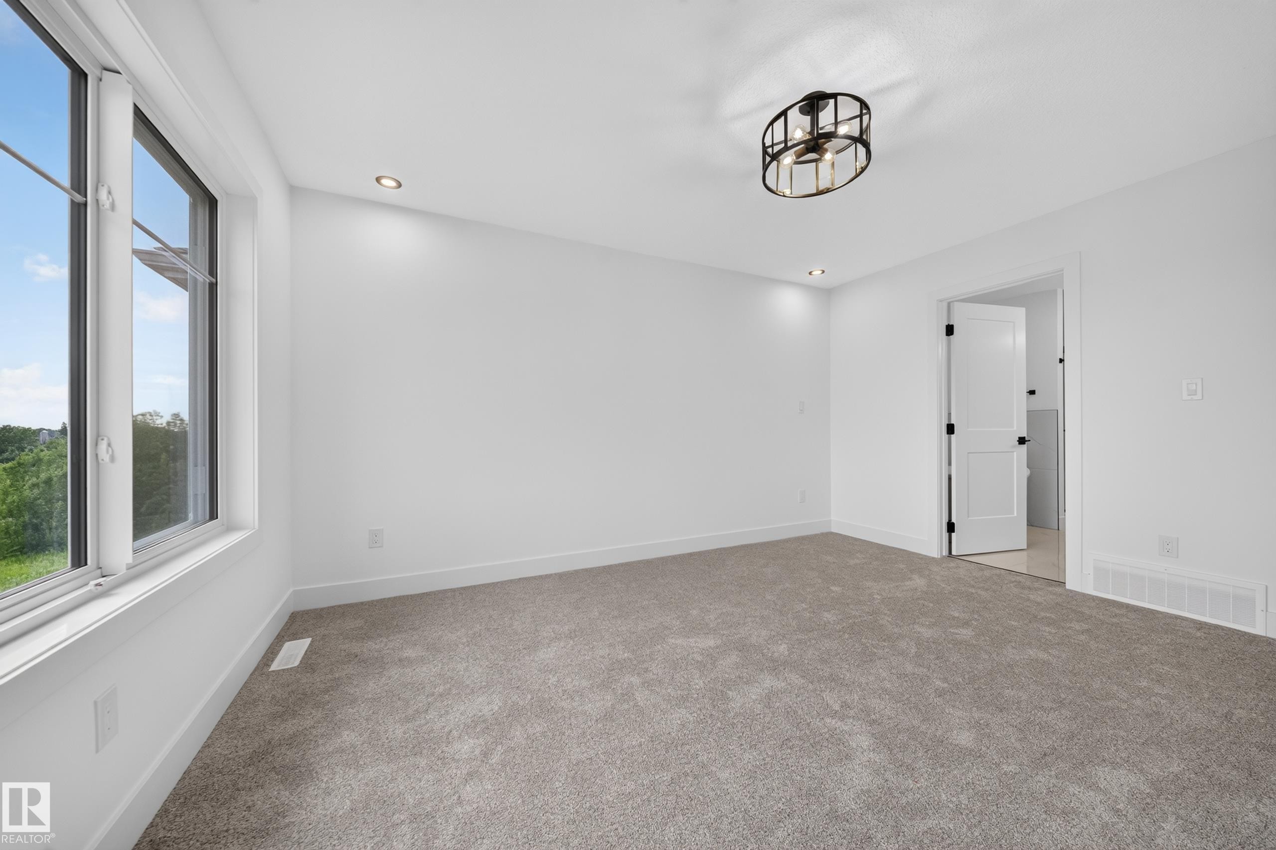Bright interior space featuring a multi-pane window, flush-mount ceiling fixture, recessed lighting, white baseboards, and neutral-toned carpeting - 803 30 Avenue, Edmonton, AB