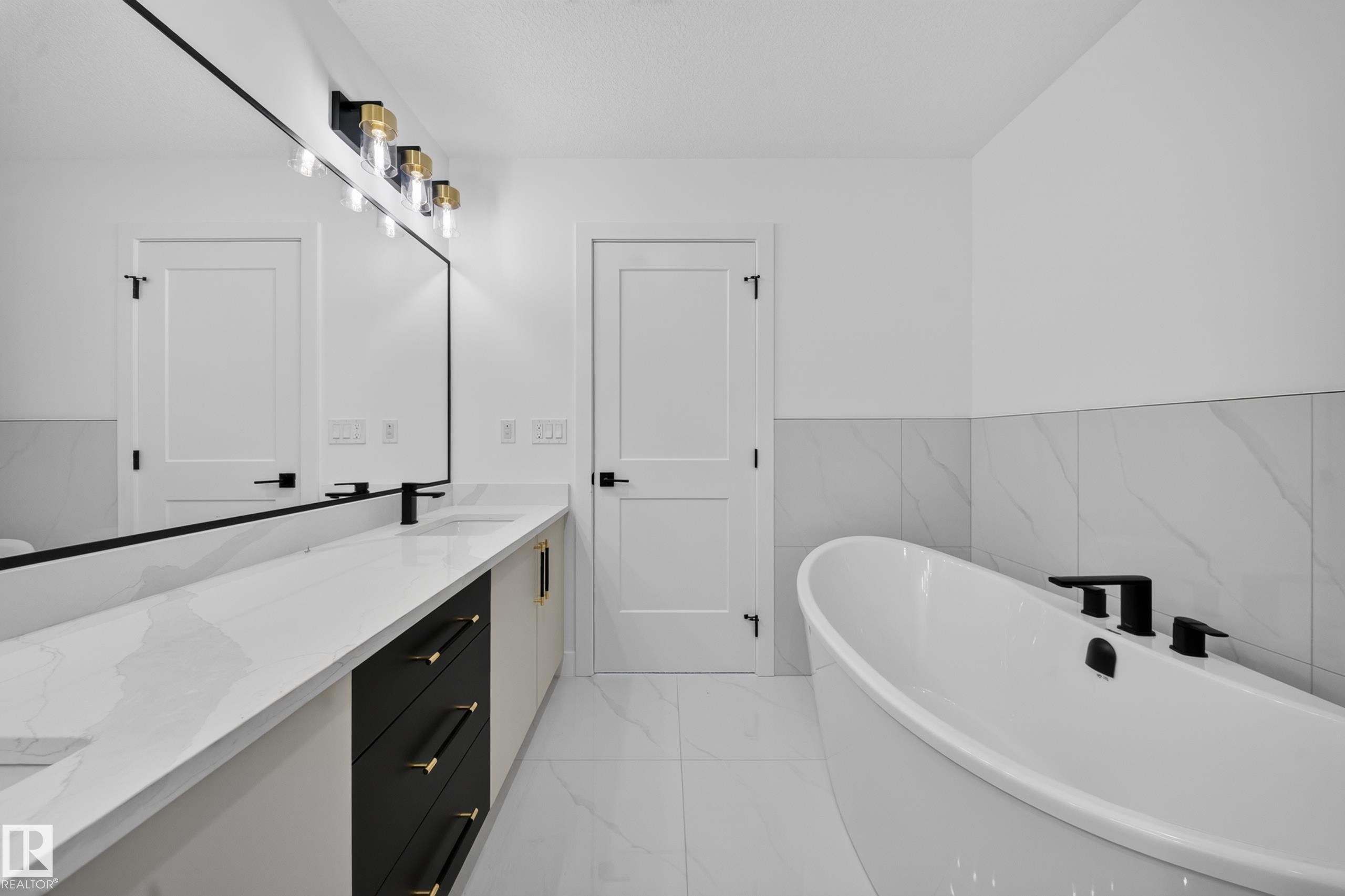 Bathroom featuring a double vanity with white countertops, integrated sinks, and matte black faucets - 803 30 Avenue, Edmonton, AB