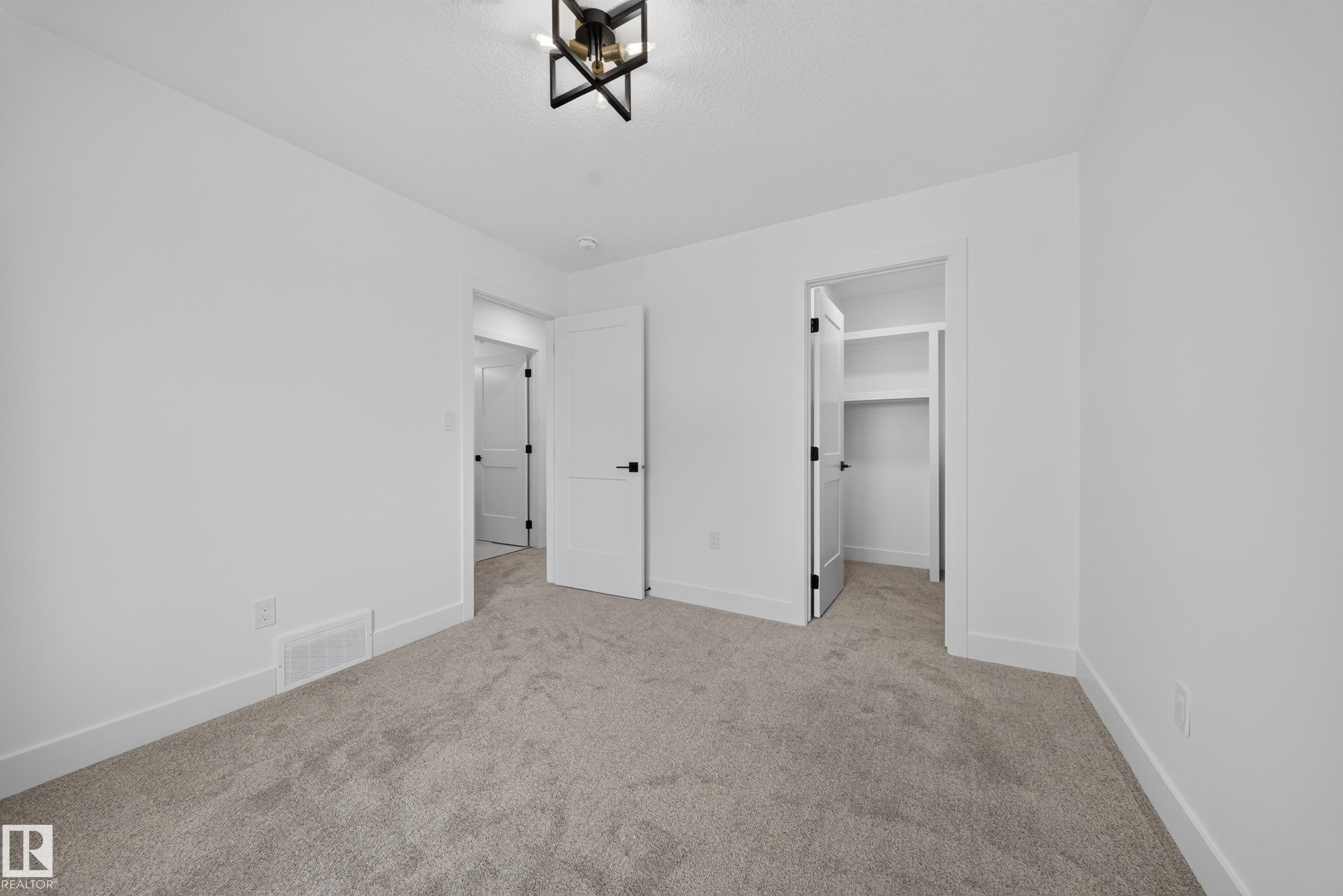 Bright room featuring a double window, modern ceiling light fixture, white walls, and gray carpet flooring - 803 30 Avenue, Edmonton, AB