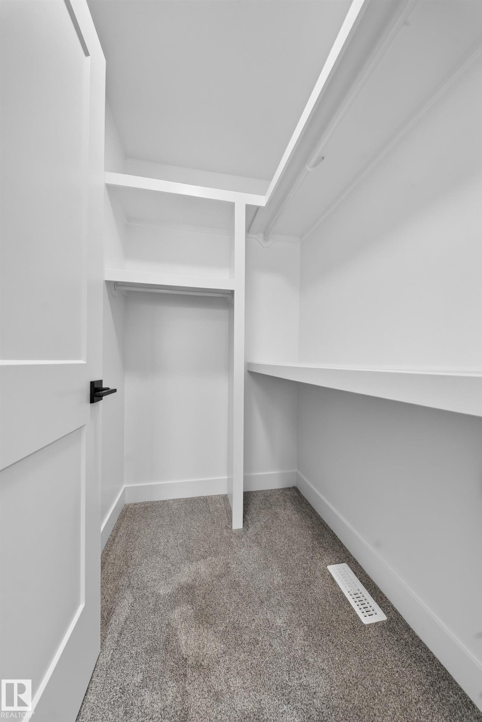 Neutral-toned carpeting throughout this space, featuring white walls, white trim, and a modern black and gold ceiling fixture - 803 30 Avenue, Edmonton, AB
