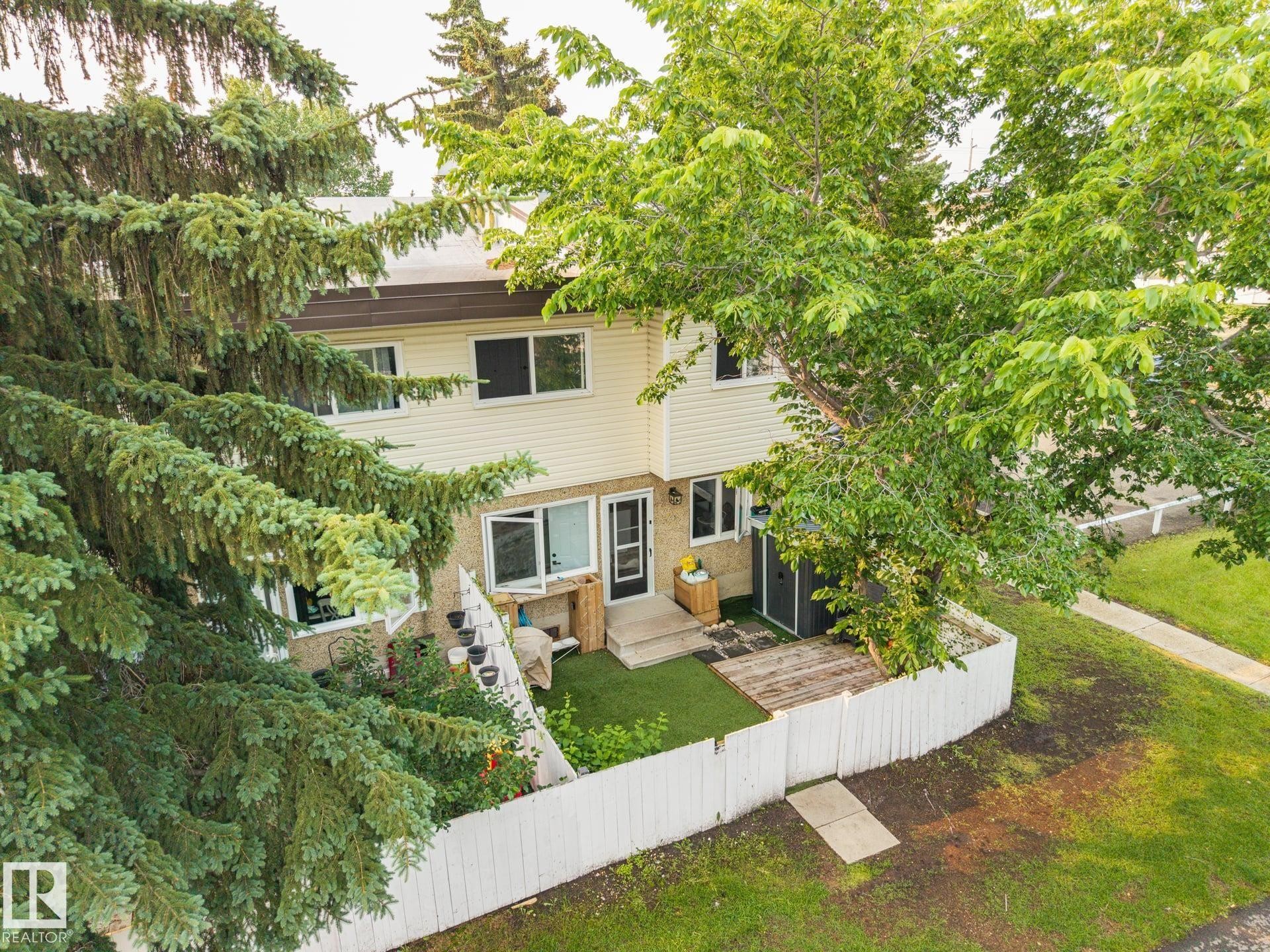 Two-story exterior with light-colored siding and dark trim windows - 105 16428 109 Street, Edmonton, AB
