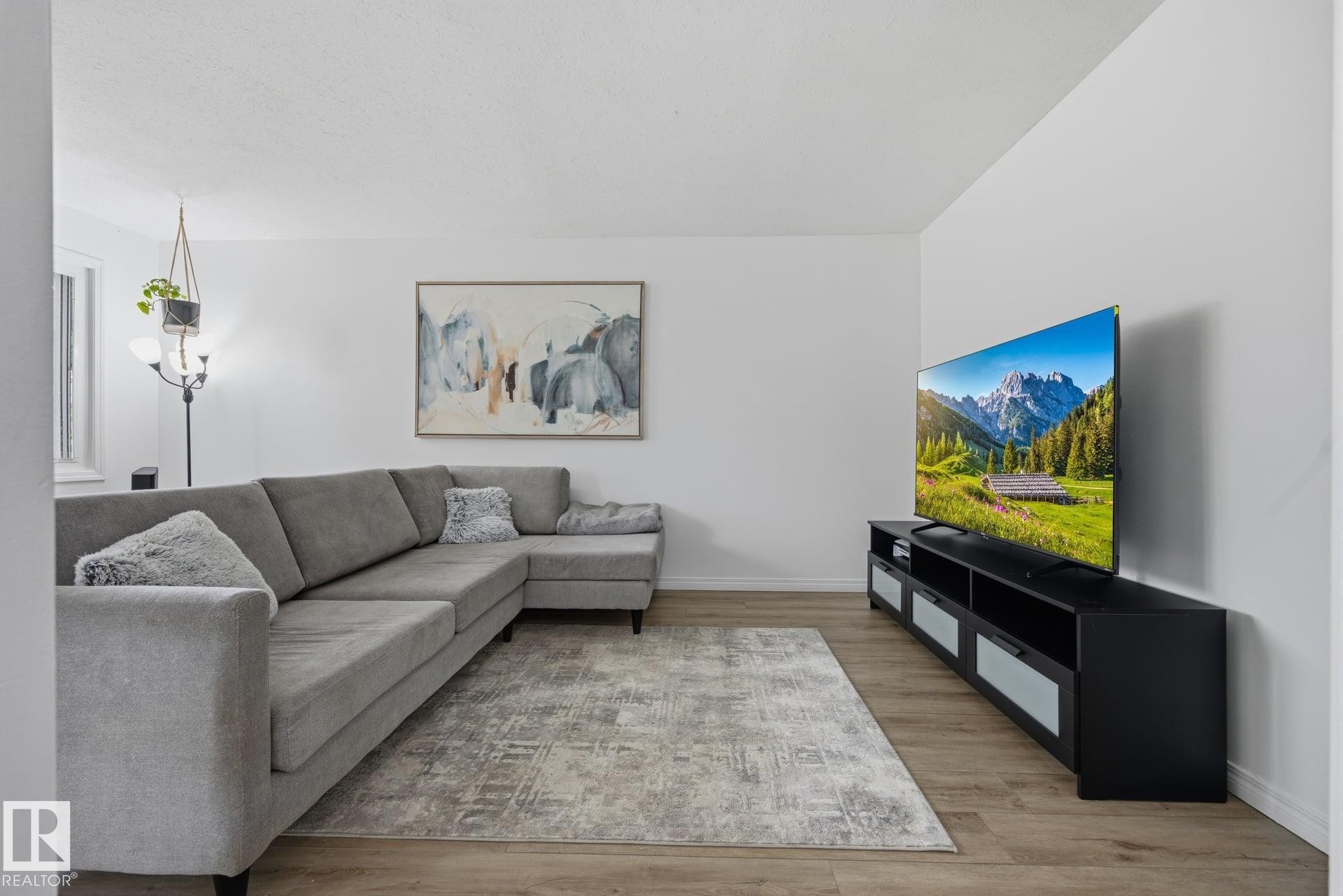 Open concept living area featuring wood-finish flooring and light-toned walls - 105 16428 109 Street, Edmonton, AB