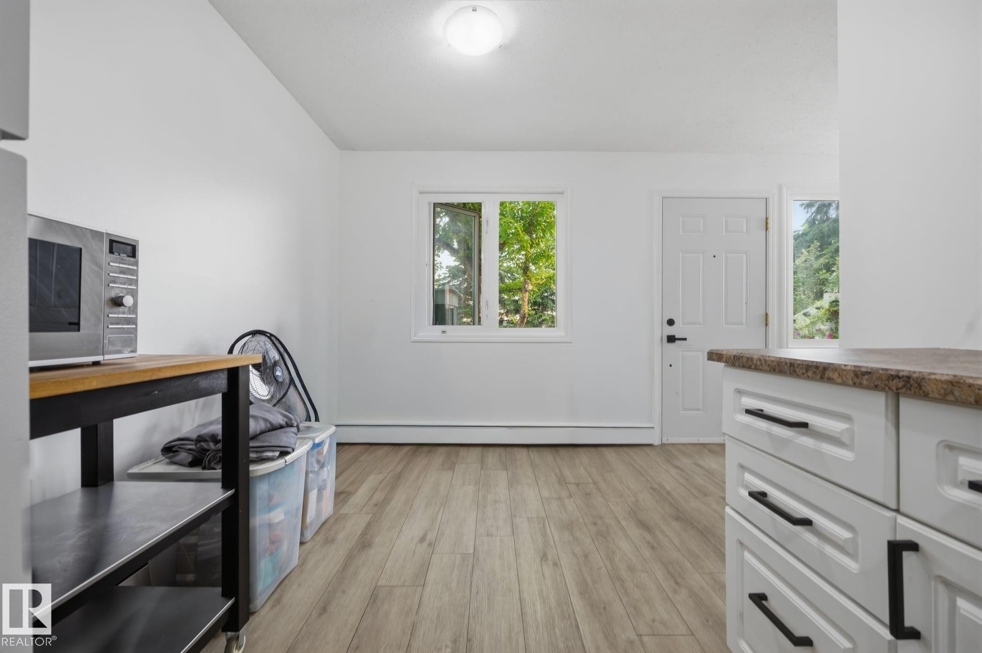 Entry area featuring wood-finish flooring, white walls, and a white paneled door with a sidelight - 105 16428 109 Street, Edmonton, AB