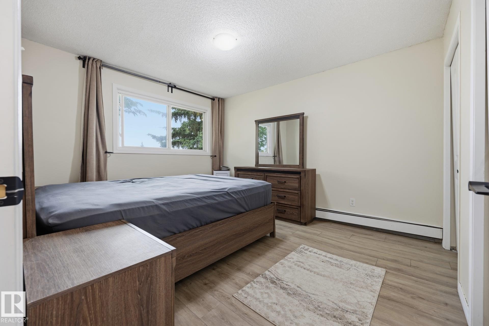 Bright room featuring wood-finish flooring and a white baseboard - 105 16428 109 Street, Edmonton, AB
