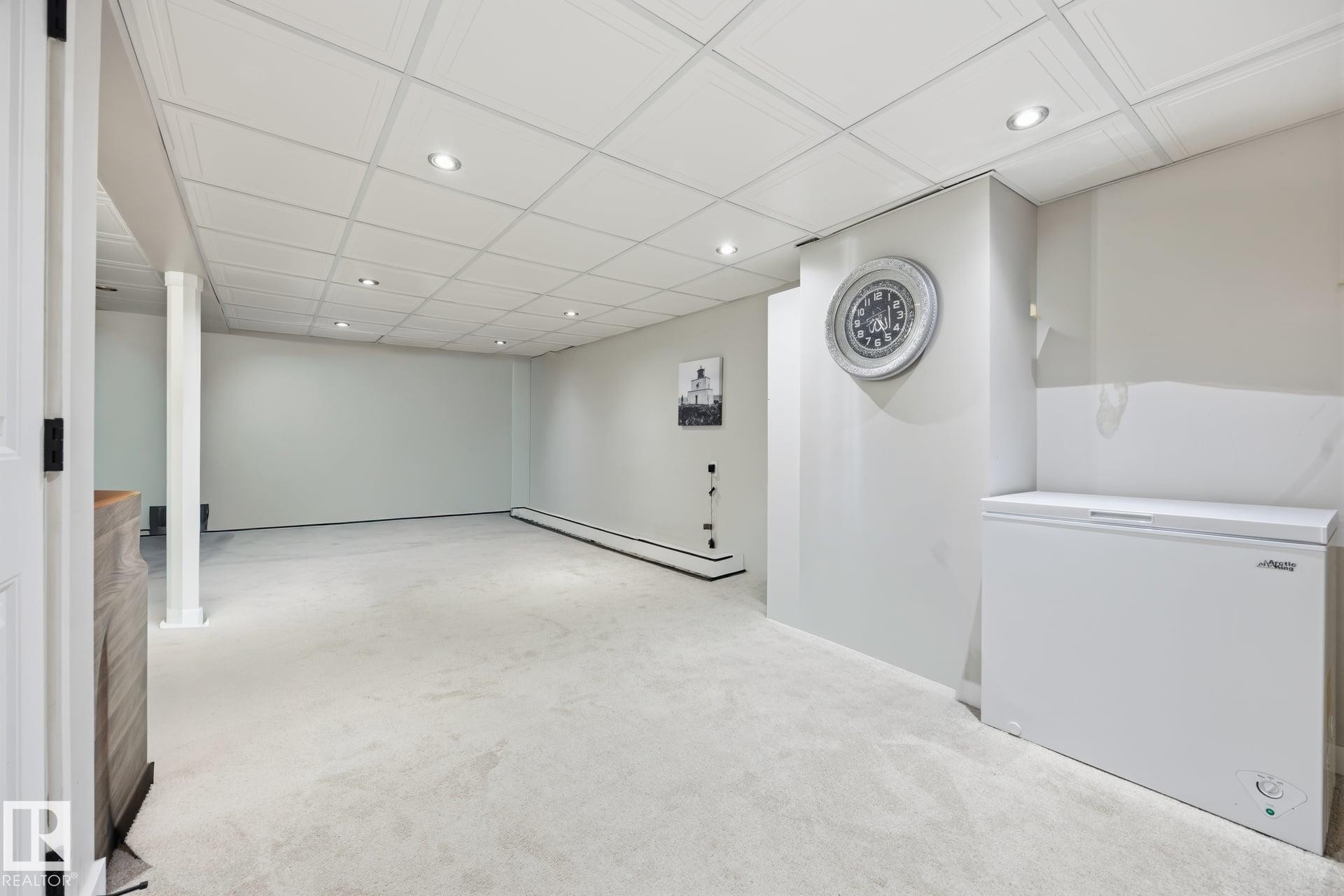 Spacious interior room featuring light-colored carpeting, recessed lighting, and a drop ceiling - 105 16428 109 Street, Edmonton, AB