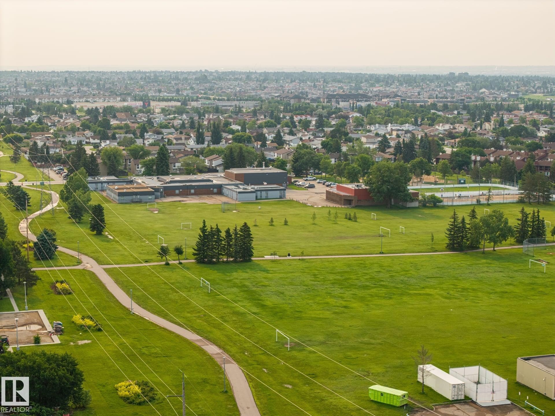 Expansive green spaces featuring walking paths, mature trees, and sports fields - 105 16428 109 Street, Edmonton, AB