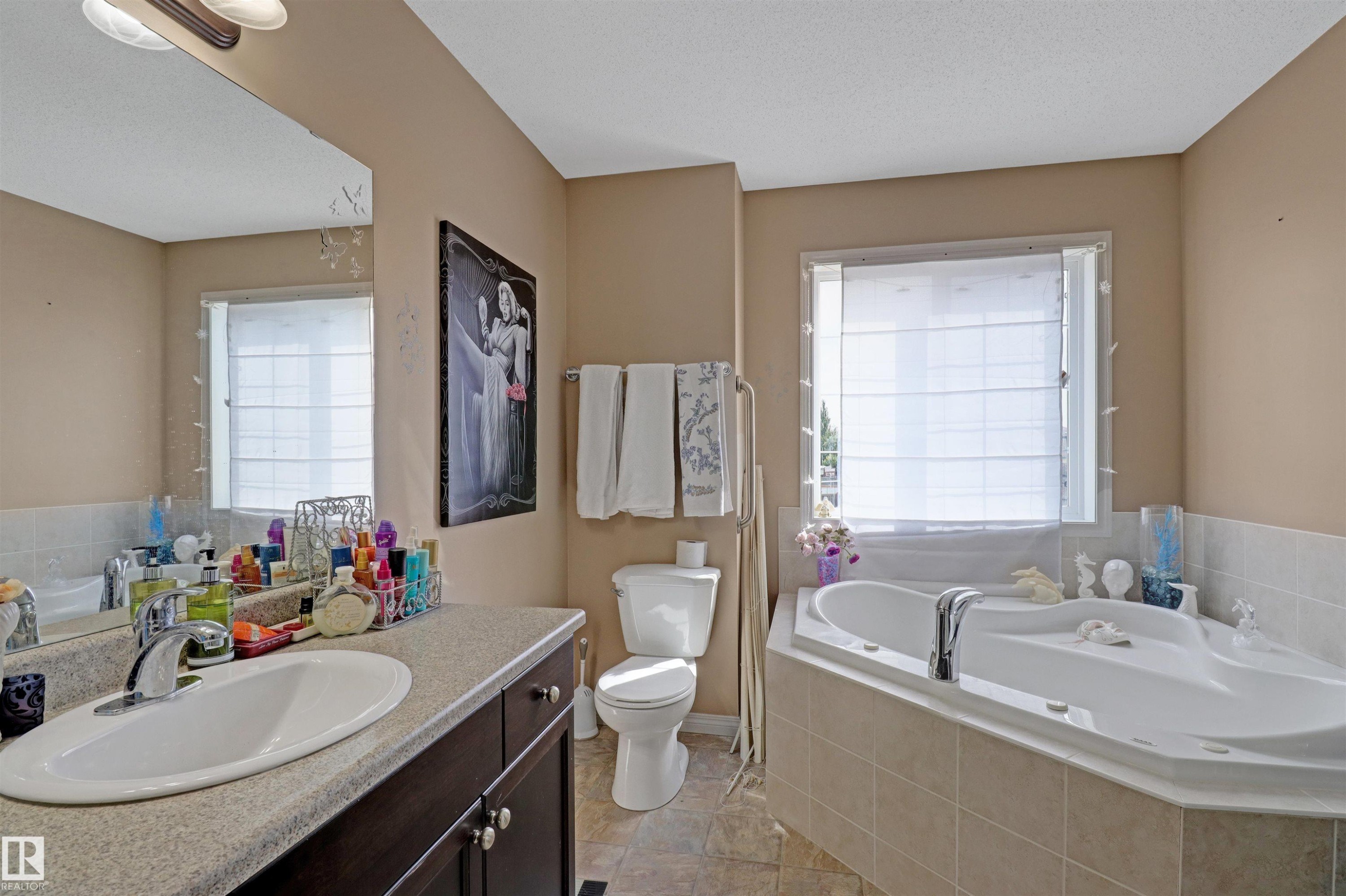 Corner soaking tub with tile surround, adjacent to a window with privacy blinds - 1216 37C Avenue Nw, Edmonton, AB - Indoor Photo Showing Bathroom