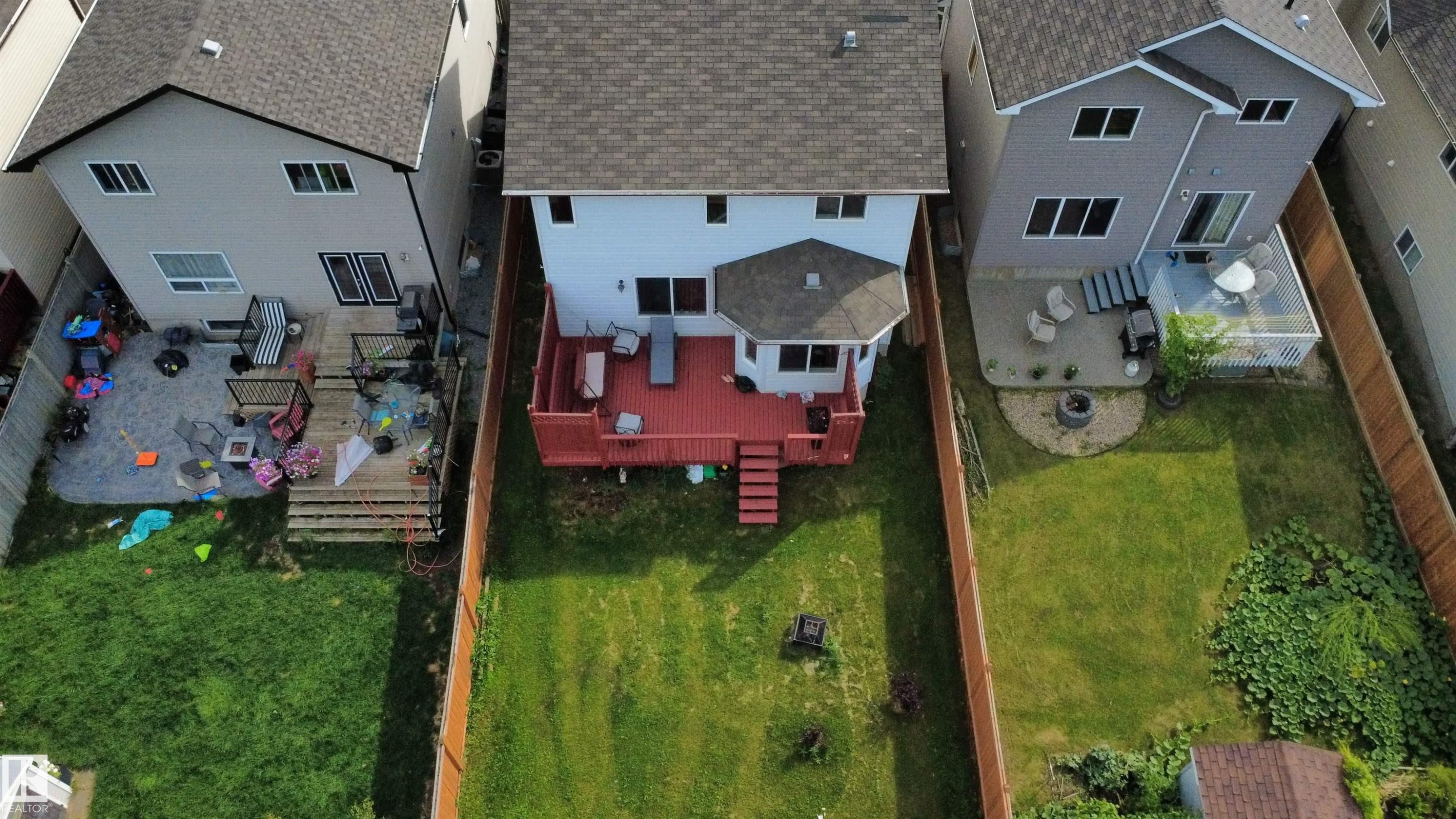 Private backyard featuring a red wood-finish deck with multiple levels and an octagonal extension, a manicured lawn, and a wooden privacy fence - 1216 37C Avenue Nw, Edmonton, AB - Outdoor