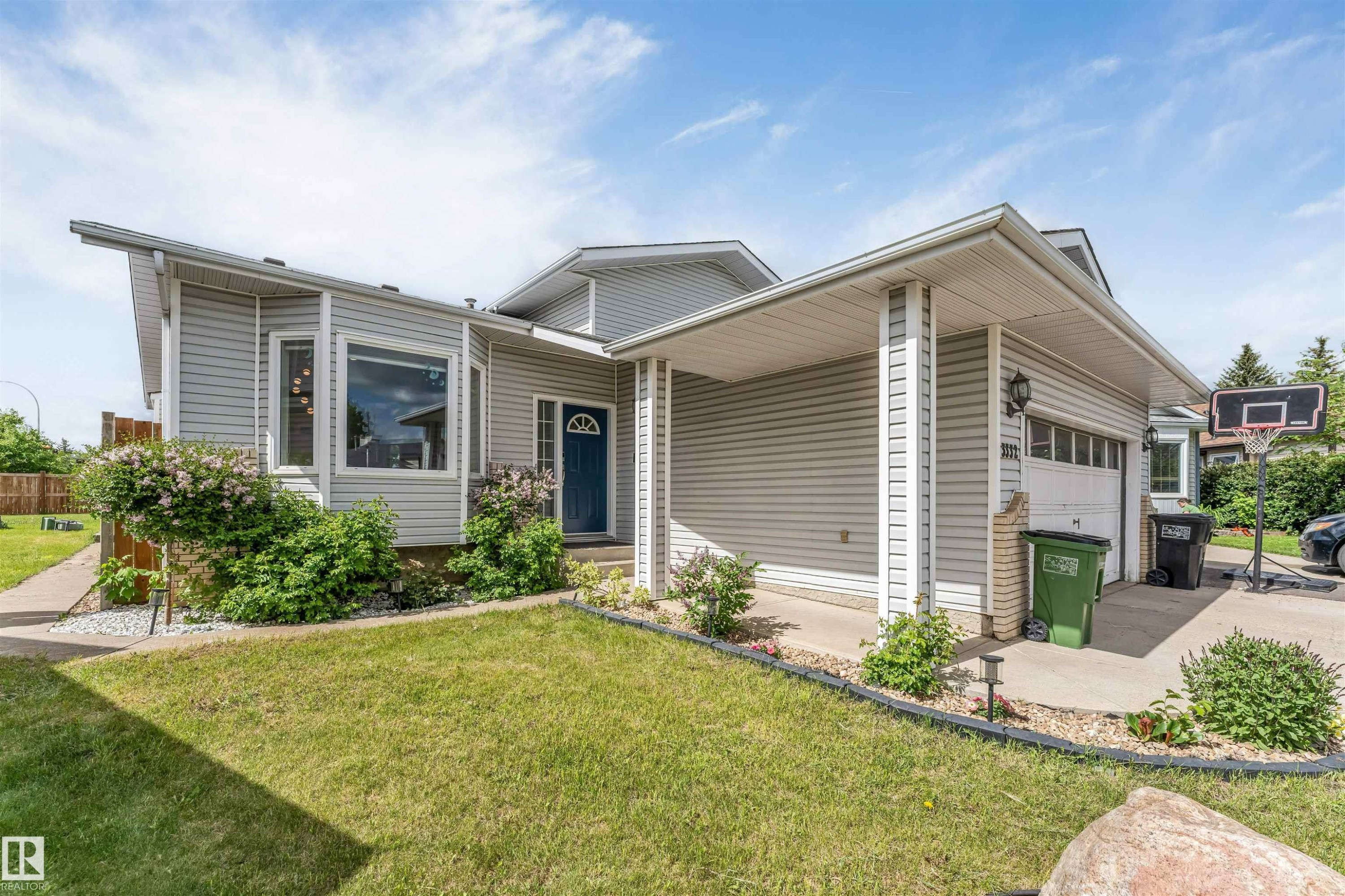Light gray siding exterior with a dark blue entry door and an attached garage - 3332 43 Street Nw, Edmonton, AB