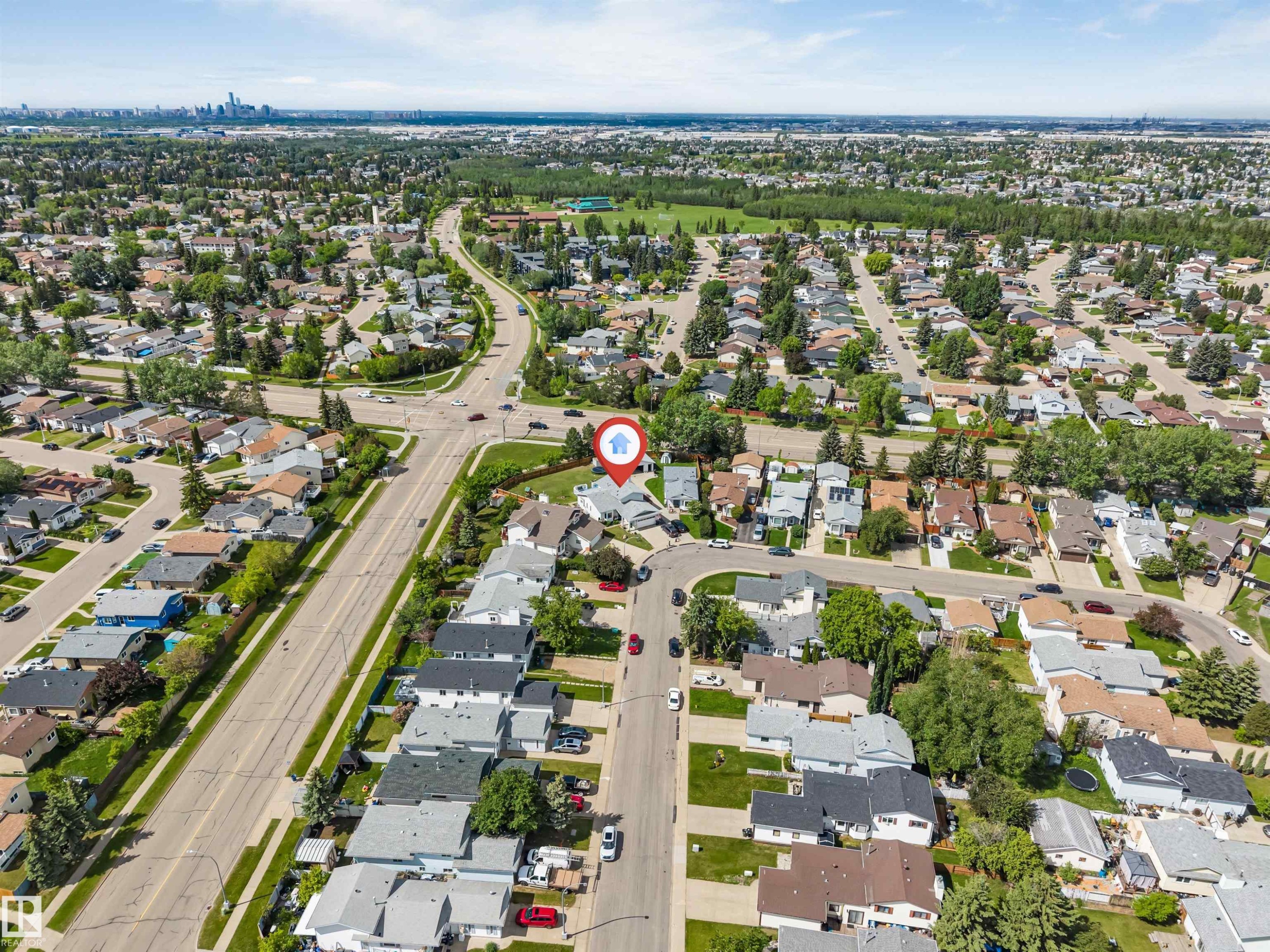 Aerial perspective showcasing a residential neighborhood with tree-lined streets and a distant city skyline - 3332 43 Street Nw, Edmonton, AB