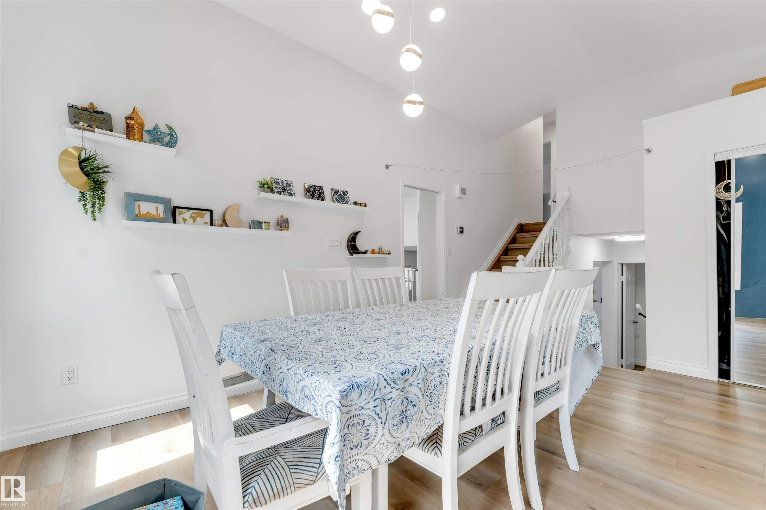 Dining area featuring wood-finish flooring, white walls, and a high ceiling with pendant lighting - 3332 43 Street Nw, Edmonton, AB