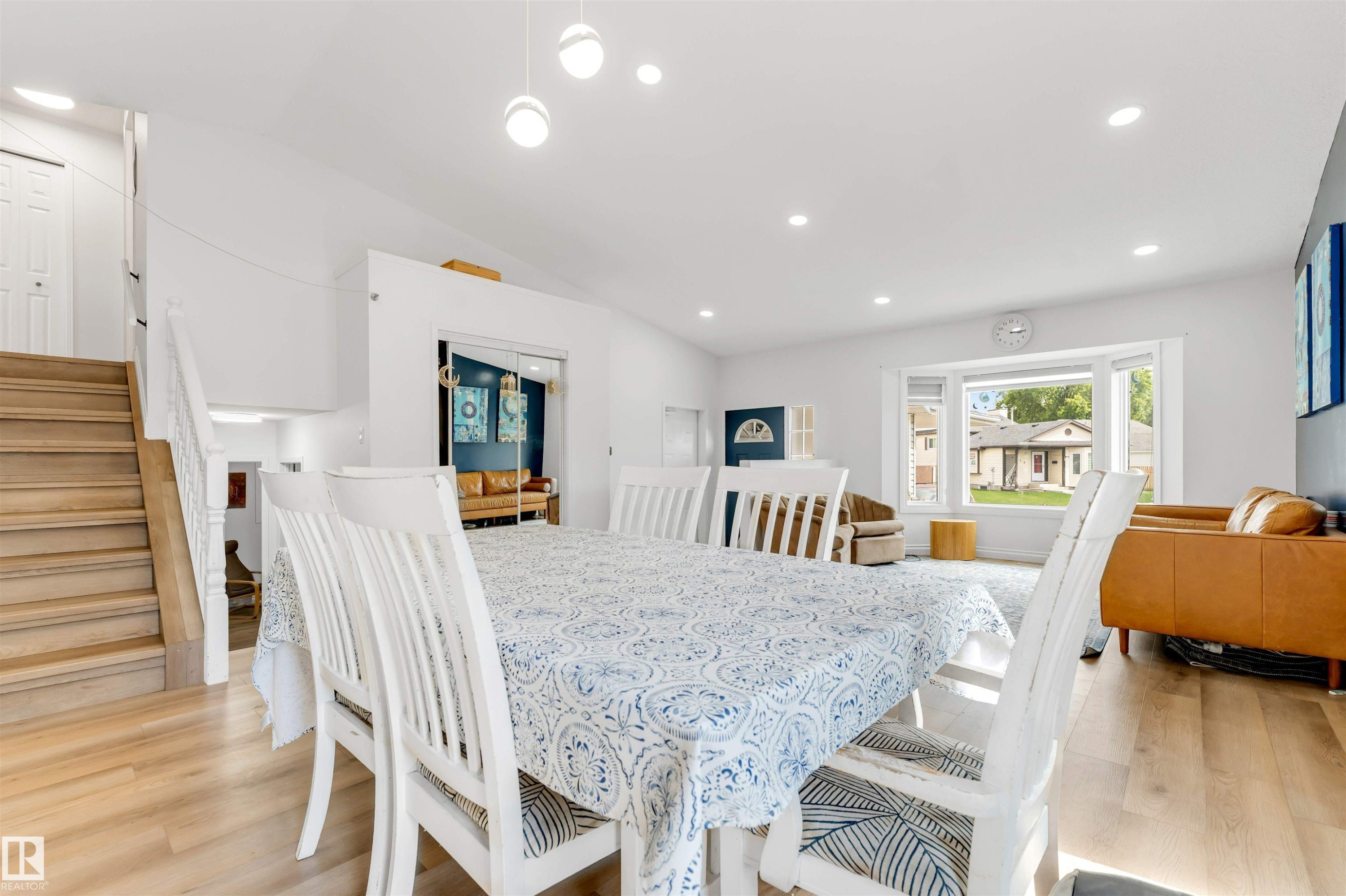 Open-concept dining and living space featuring wood-finish flooring, recessed lighting, and a bay window - 3332 43 Street Nw, Edmonton, AB