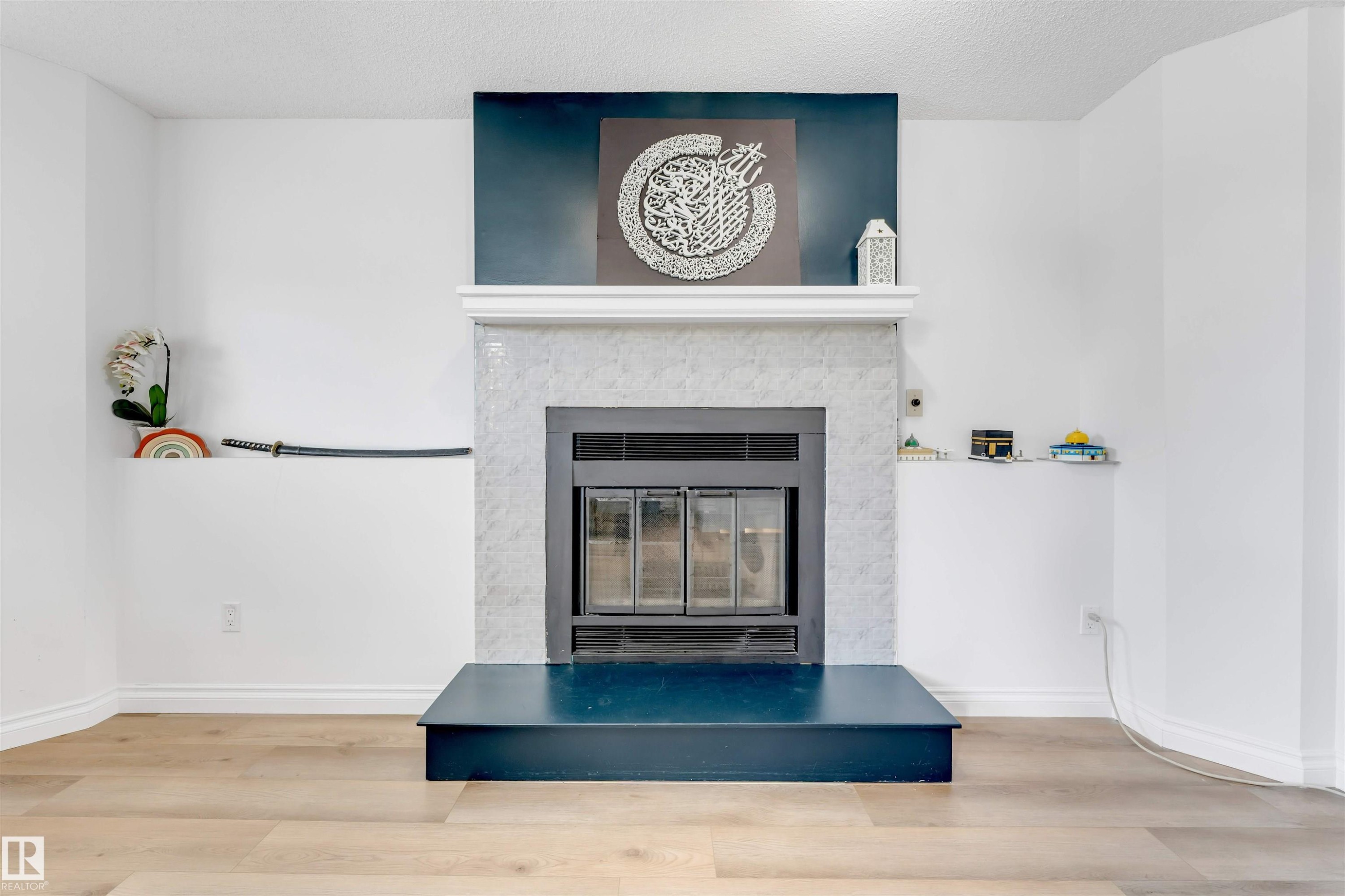Fireplace with a white tile surround, a dark hearth, and an integrated firebox - 3332 43 Street Nw, Edmonton, AB