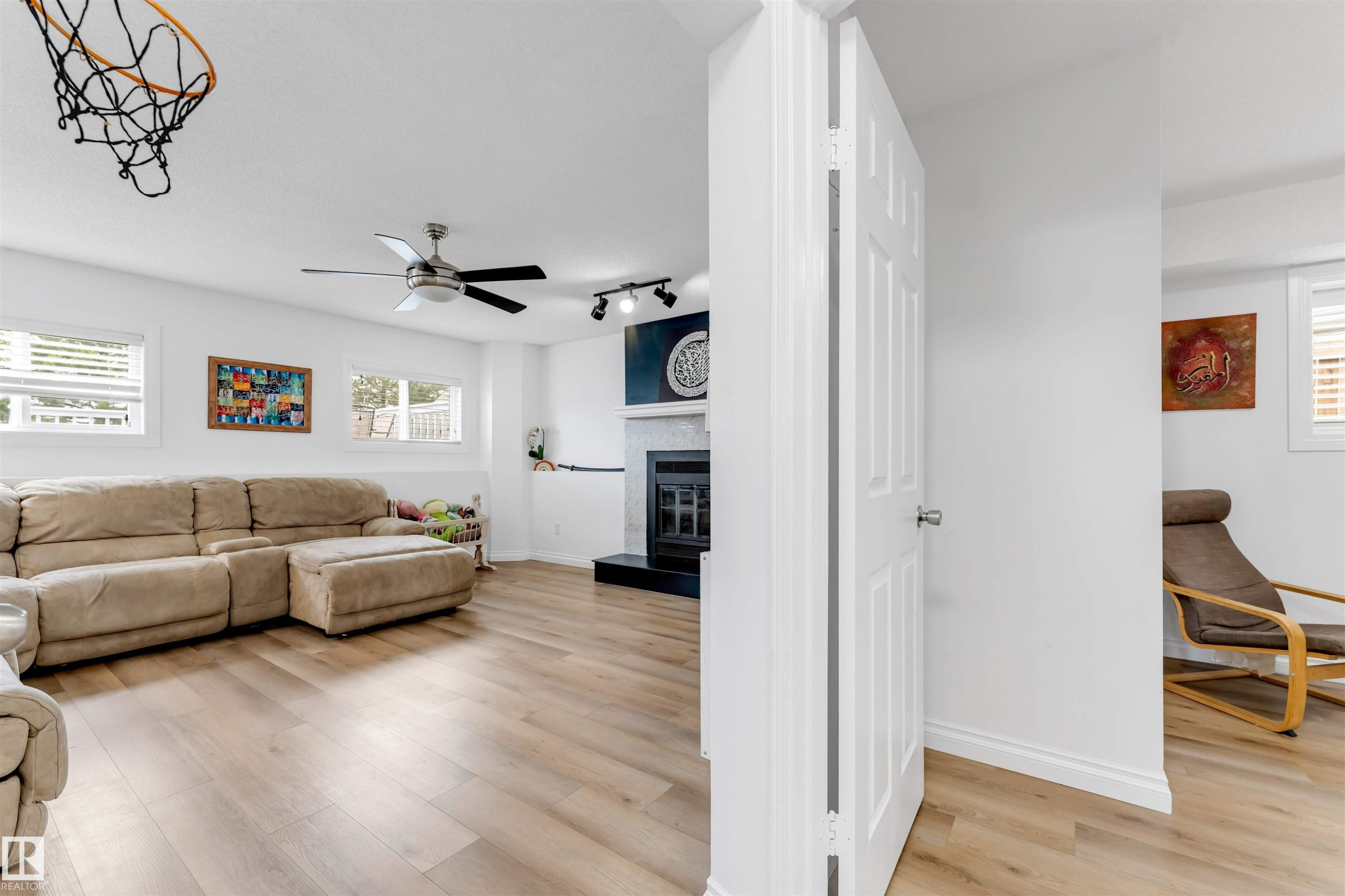 Spacious interior featuring wood-finish flooring, white walls, and multiple windows with white blinds - 3332 43 Street Nw, Edmonton, AB
