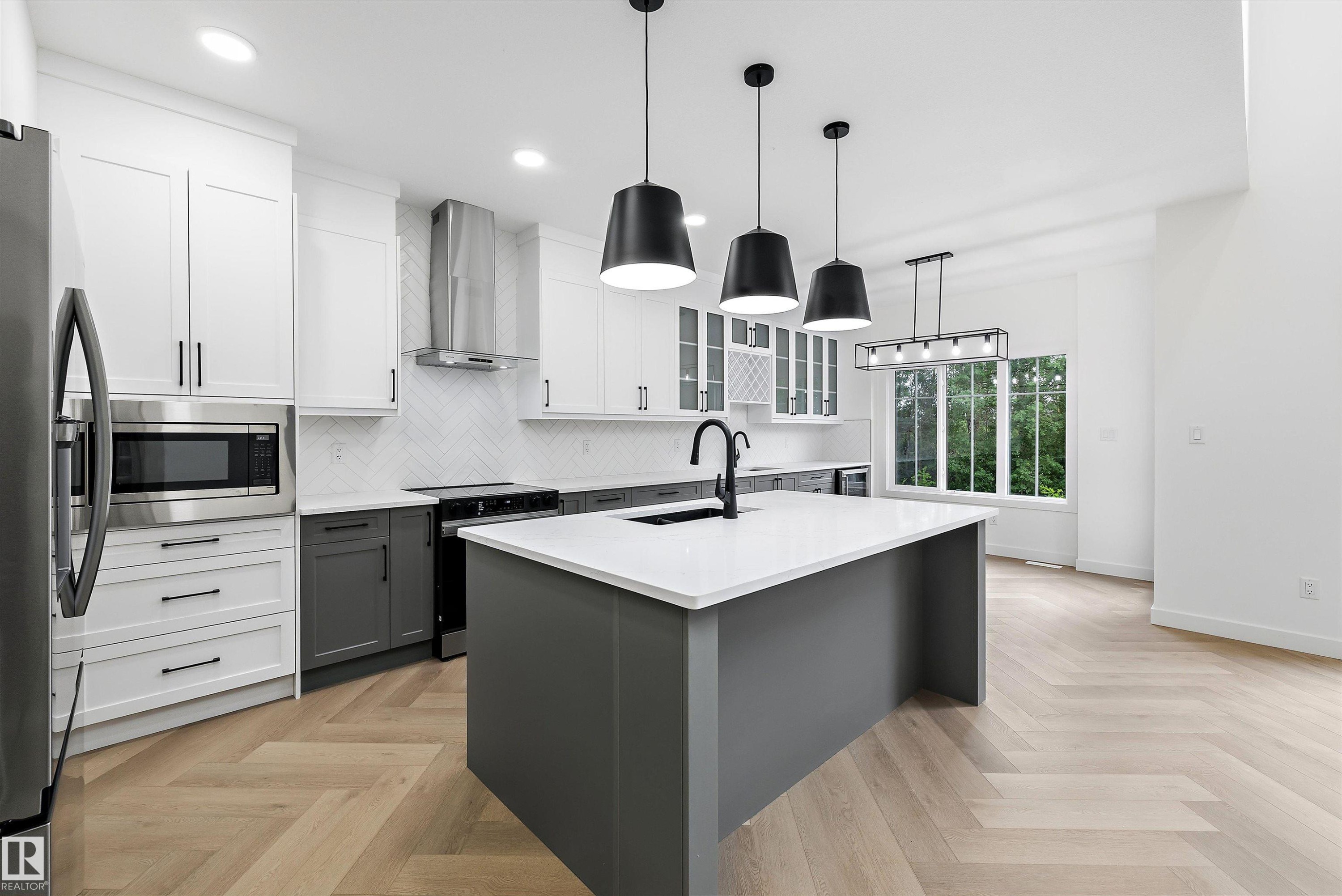 Modern kitchen featuring a large central island with a solid surface countertop and matte black fixtures - 917 Elderberry Landing, Edmonton, AB