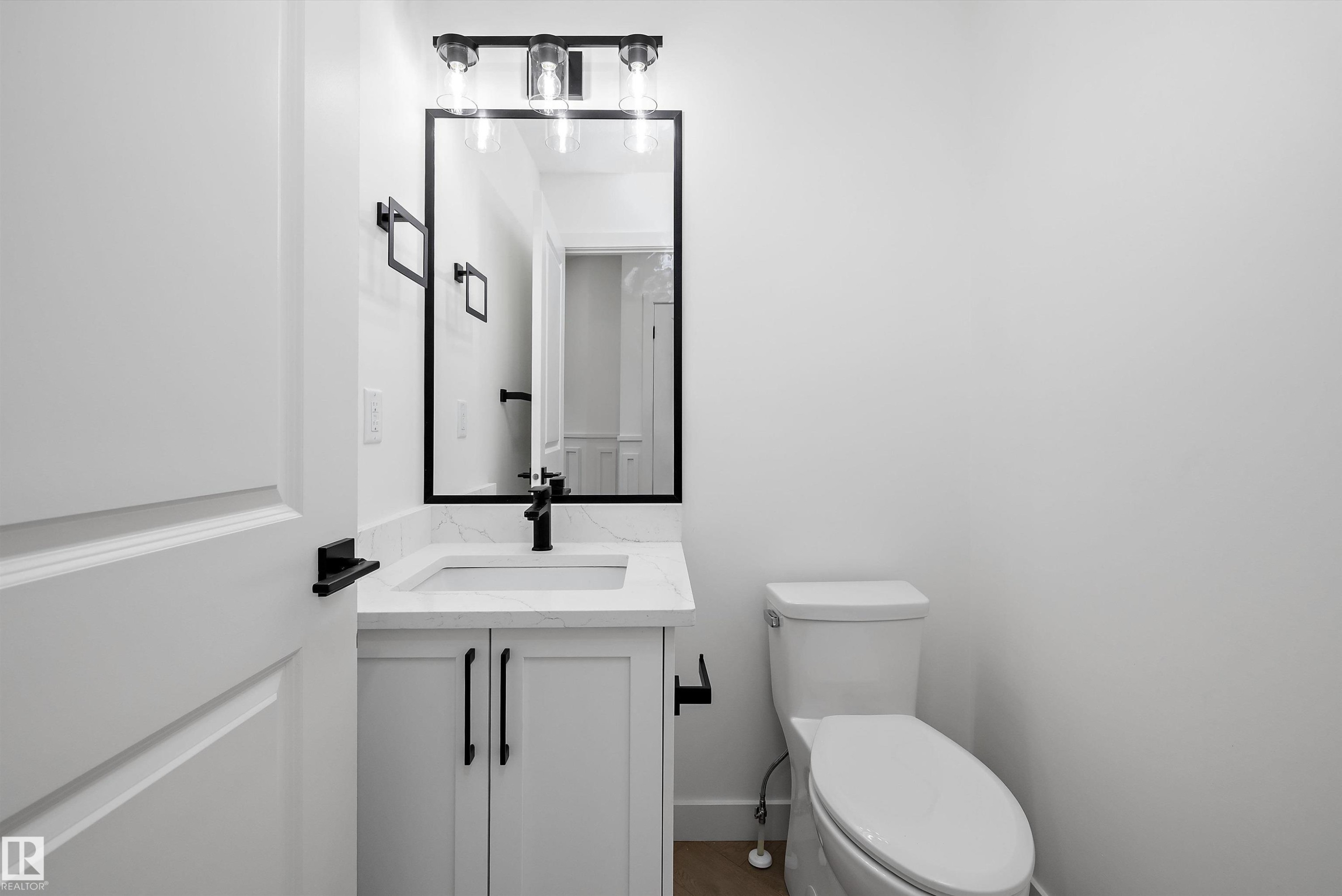Bathroom featuring a white vanity with panel cabinetry, a white countertop, an undermount sink, and black hardware - 917 Elderberry Landing, Edmonton, AB