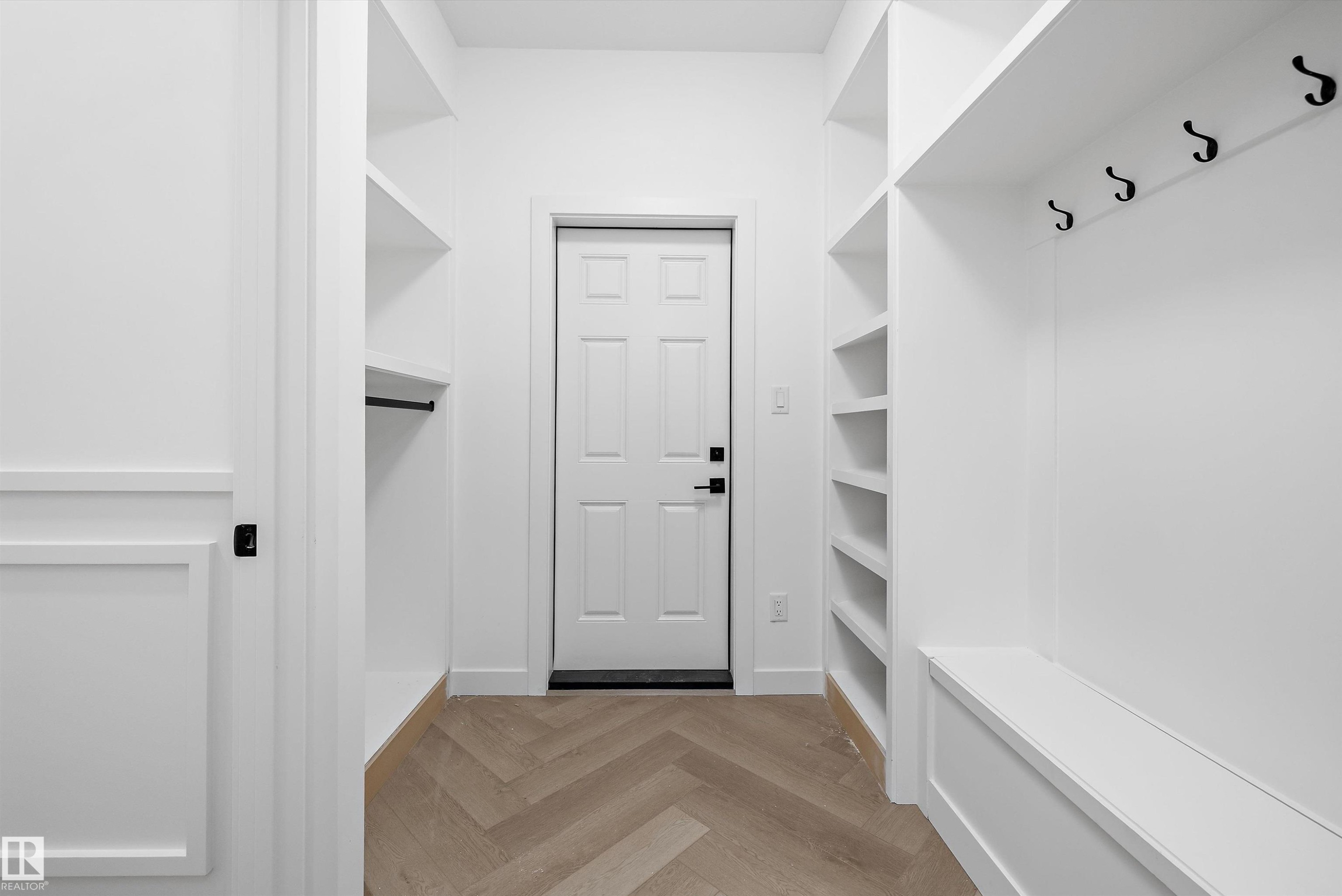 Dedicated mudroom entryway featuring herringbone wood-finish flooring, built-in shelving, integrated bench seating, and wall-mounted coat hooks - 917 Elderberry Landing, Edmonton, AB