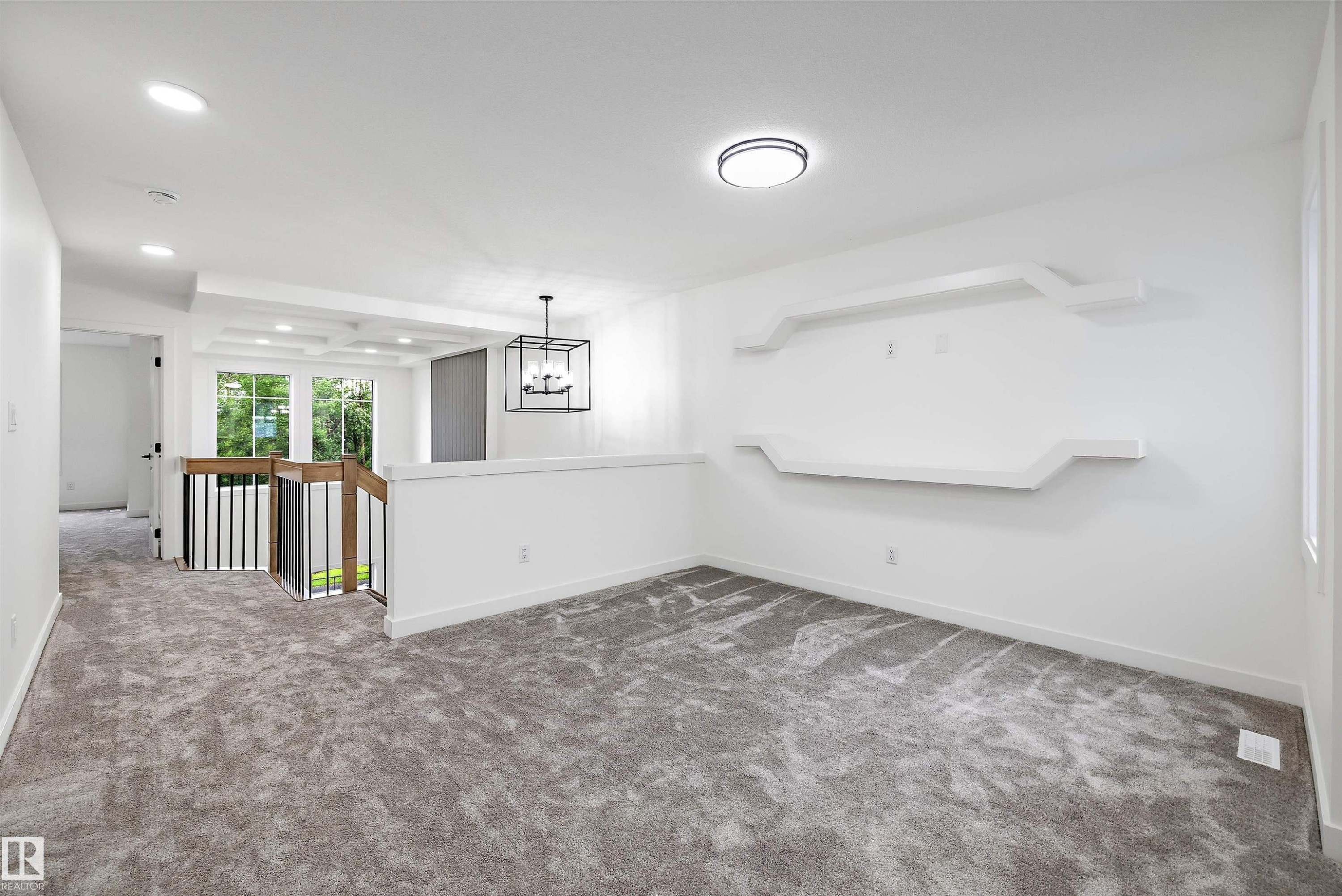 Carpeted loft space featuring built-in display shelving, a contemporary chandelier, recessed lighting, and white trim throughout - 917 Elderberry Landing, Edmonton, AB