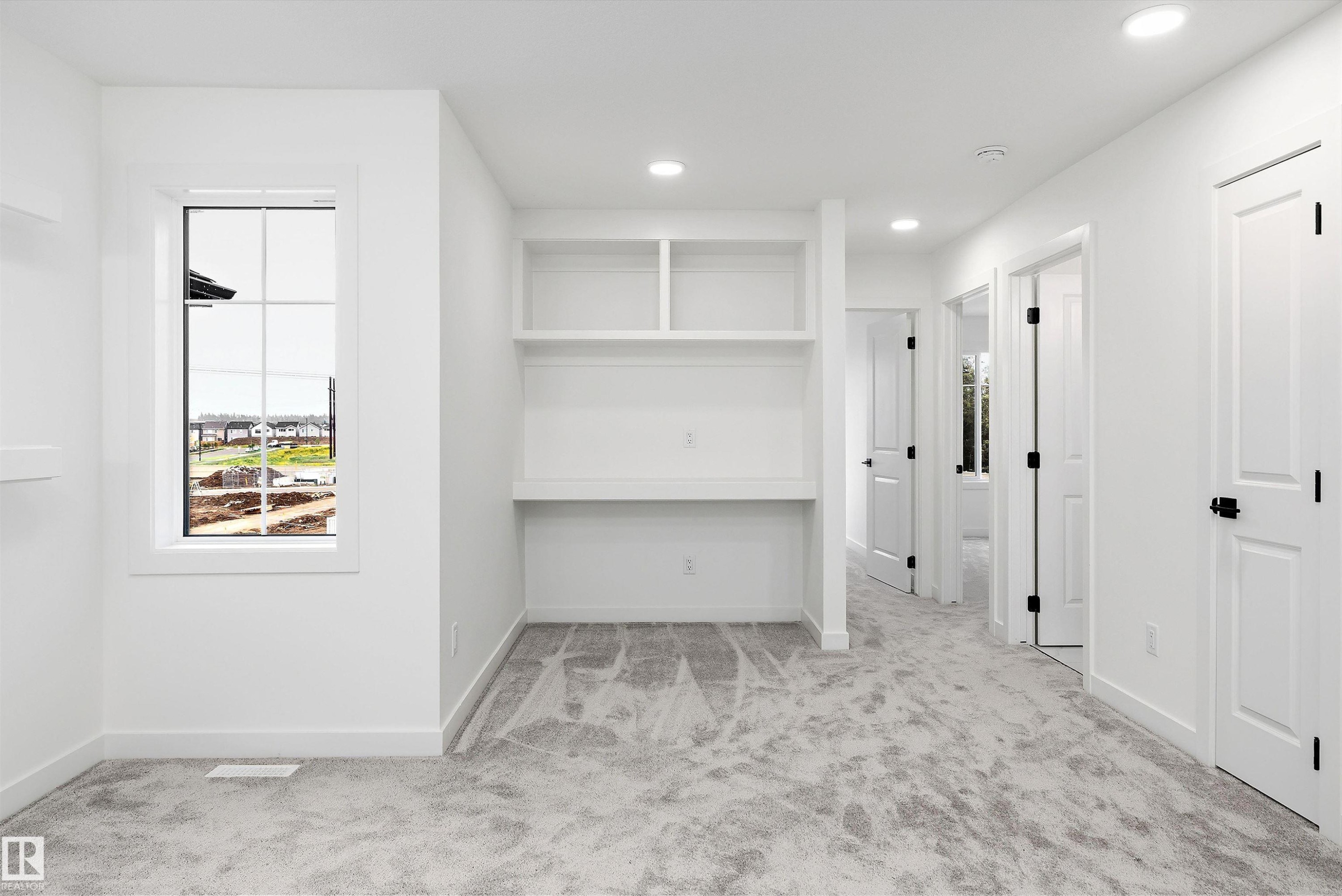 Bright room with built-in desk and shelving, recessed lighting, and light gray patterned carpeting - 917 Elderberry Landing, Edmonton, AB