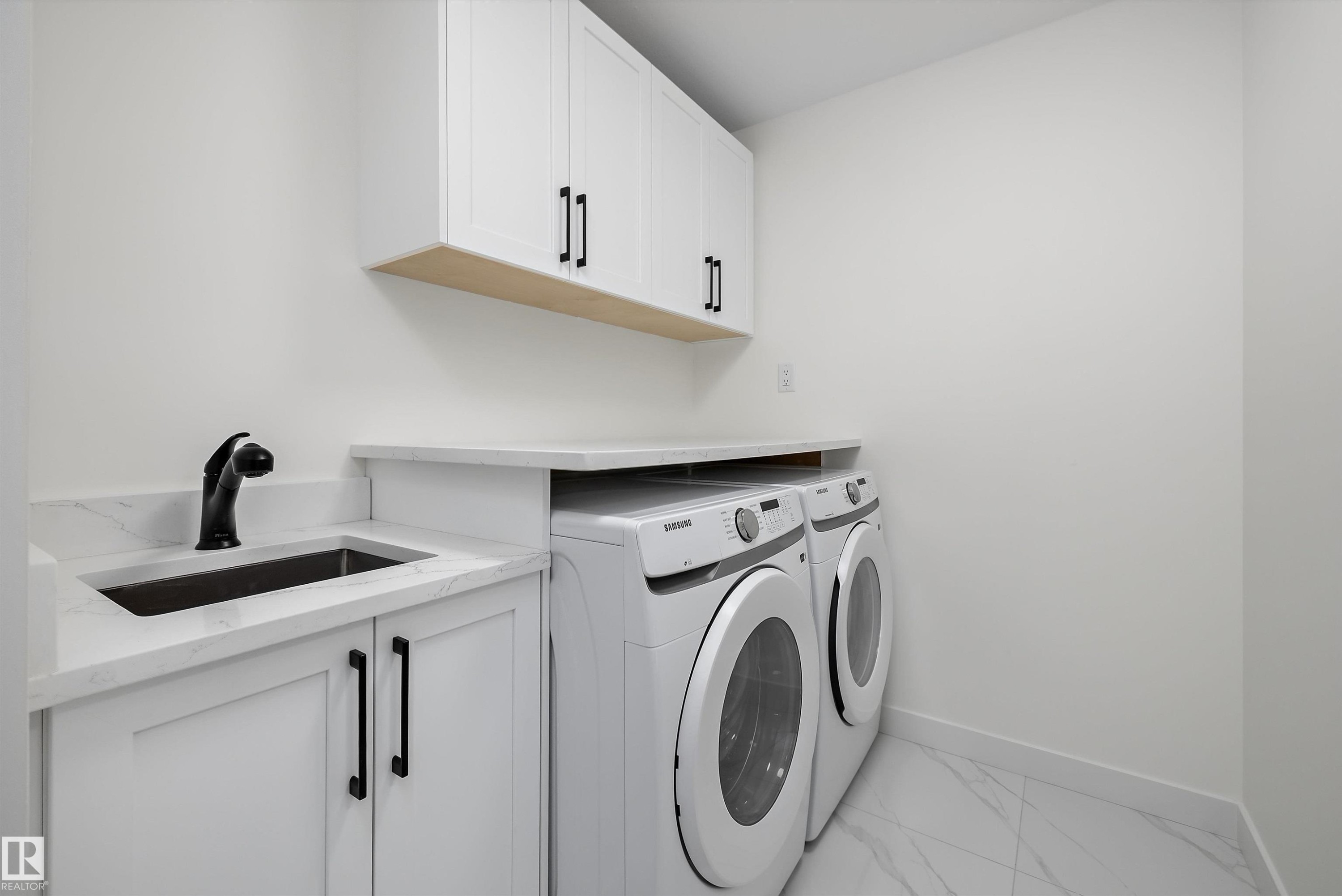 Laundry area featuring white cabinetry, a utility sink with a matte black faucet, and white countertop space - 917 Elderberry Landing, Edmonton, AB