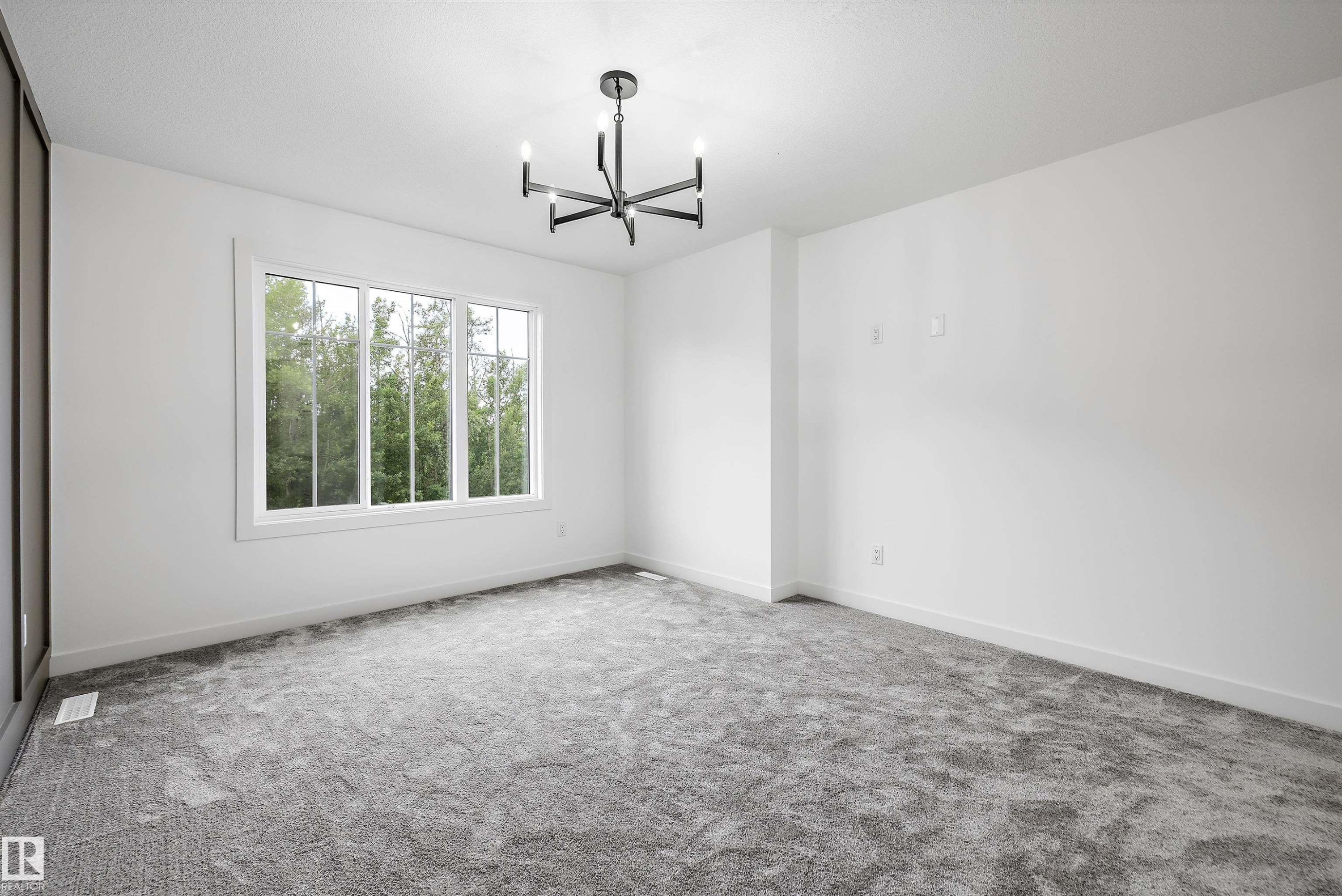Spacious interior room featuring a multi-pane window, suspended four-light chandelier, light gray carpeting, crisp white walls, and white baseboards - 917 Elderberry Landing, Edmonton, AB