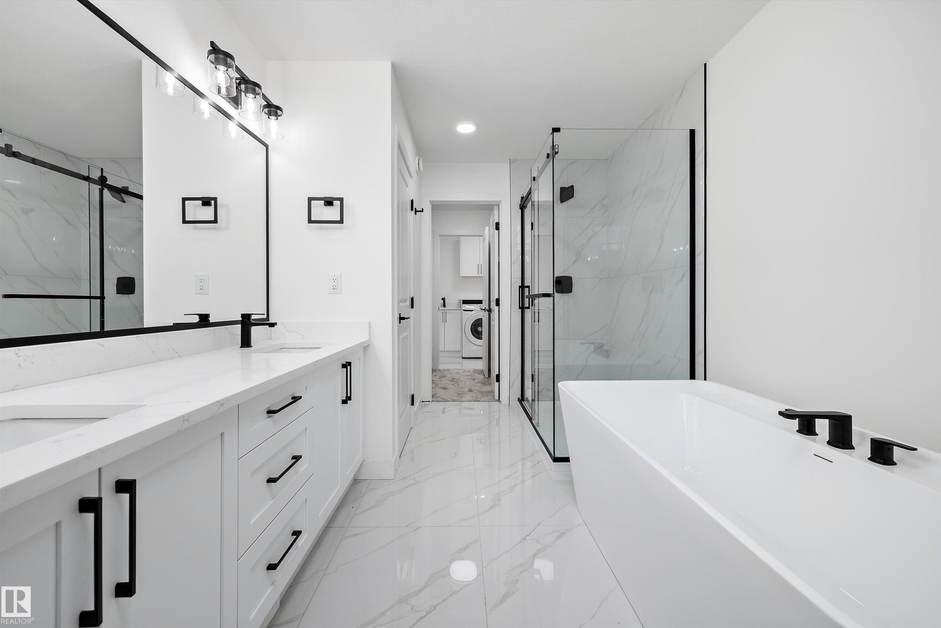 Contemporary bathroom featuring a freestanding soaking tub with matte black fixtures, a glass-enclosed shower, a dual vanity with white cabinetry and quartz countertops, and marble-look floor tiling - 917 Elderberry Landing, Edmonton, AB