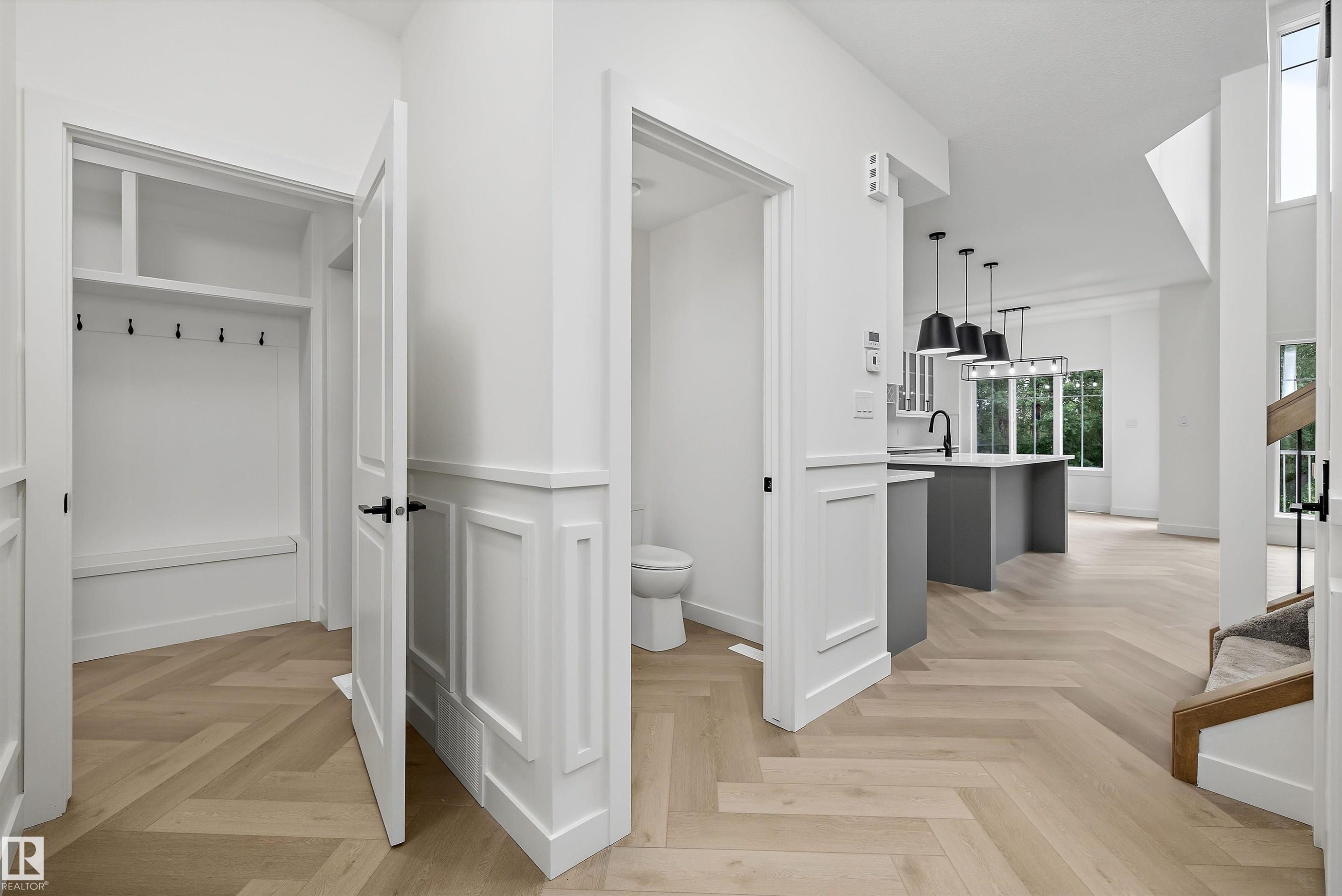 Herringbone wood-finish flooring extending through the entry and main living area - 917 Elderberry Landing, Edmonton, AB